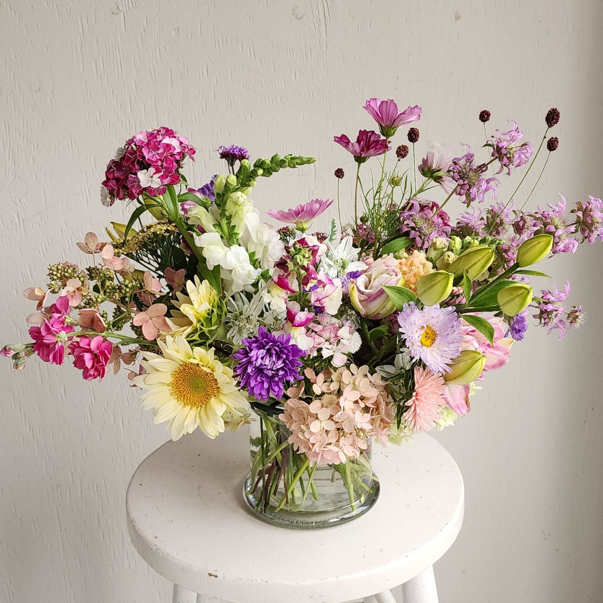 Mixed bouquet of pink, purple, and white flowers in a glass vase