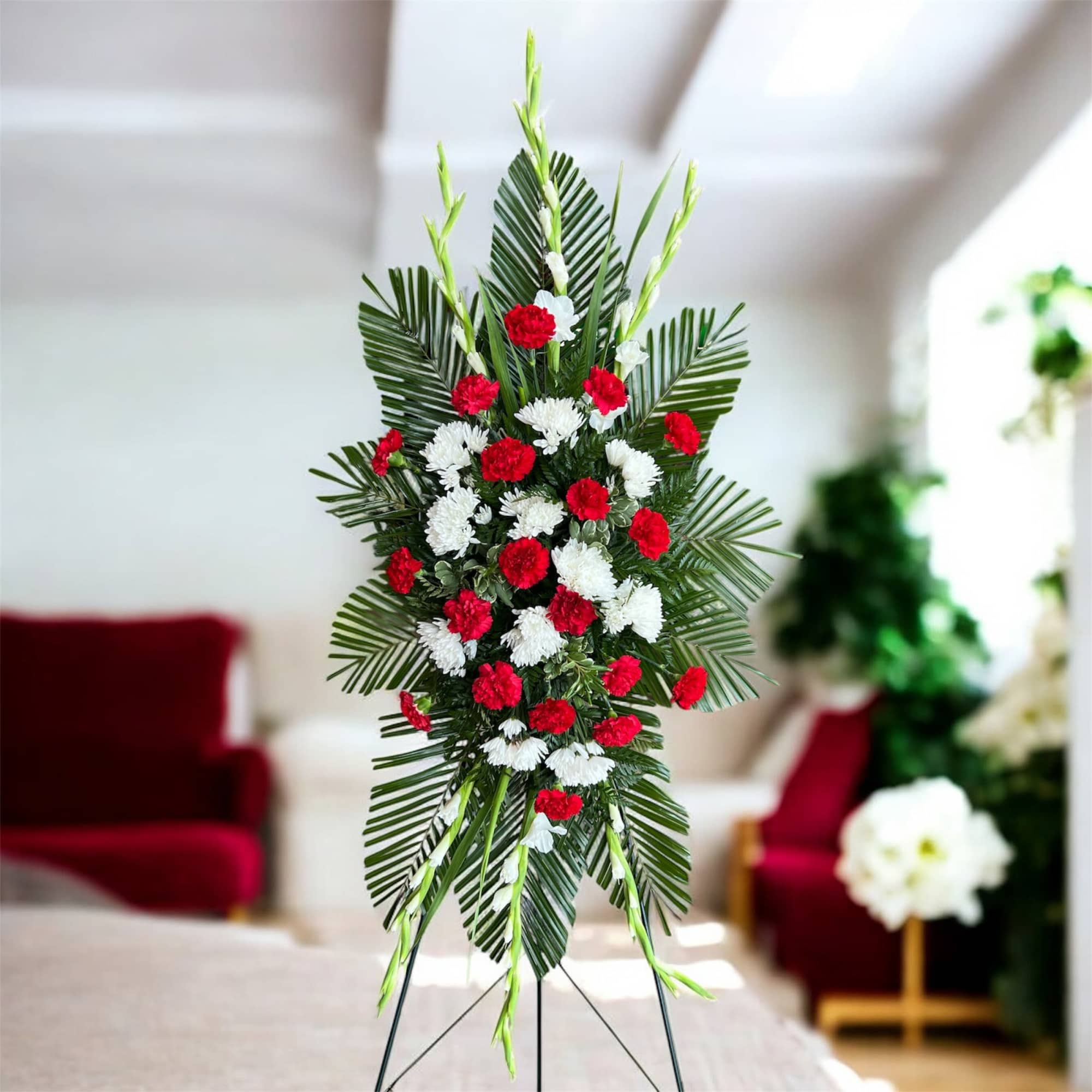 Standing floral spray with red and white carnations on palm leaves