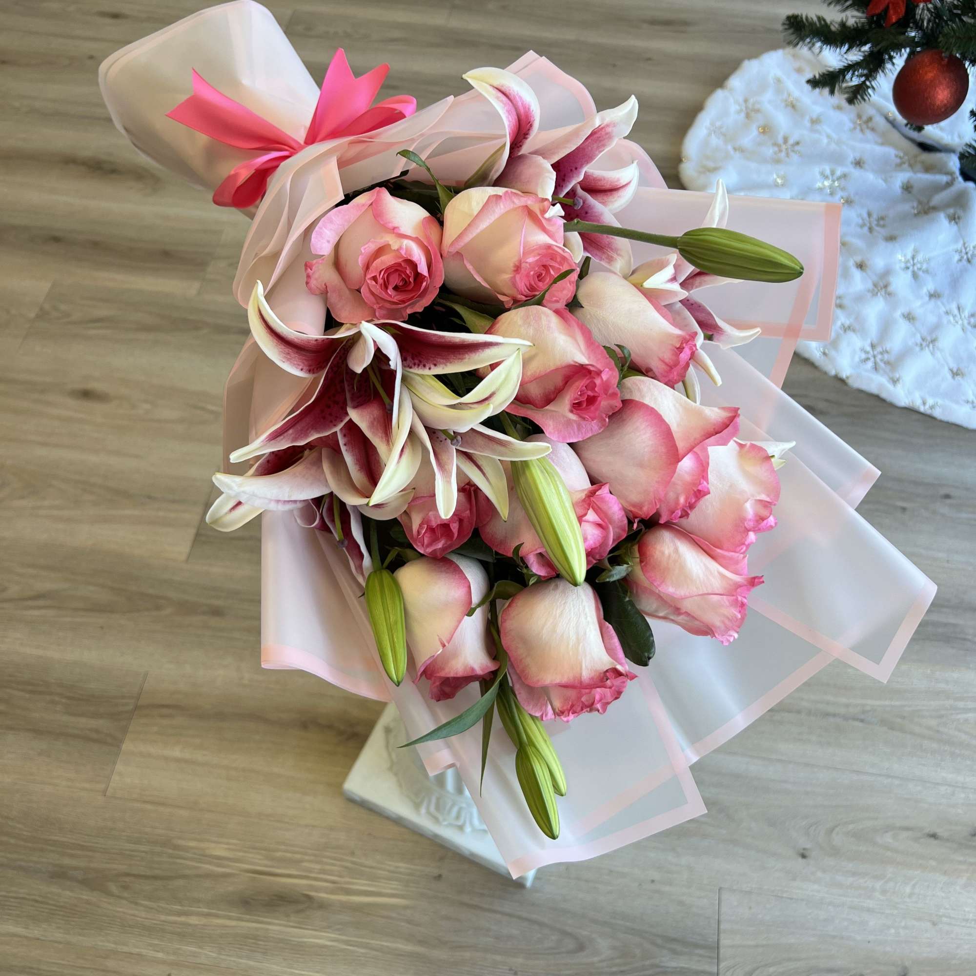 Pink roses and lilies wrapped in pale pink paper with a bright ribbon