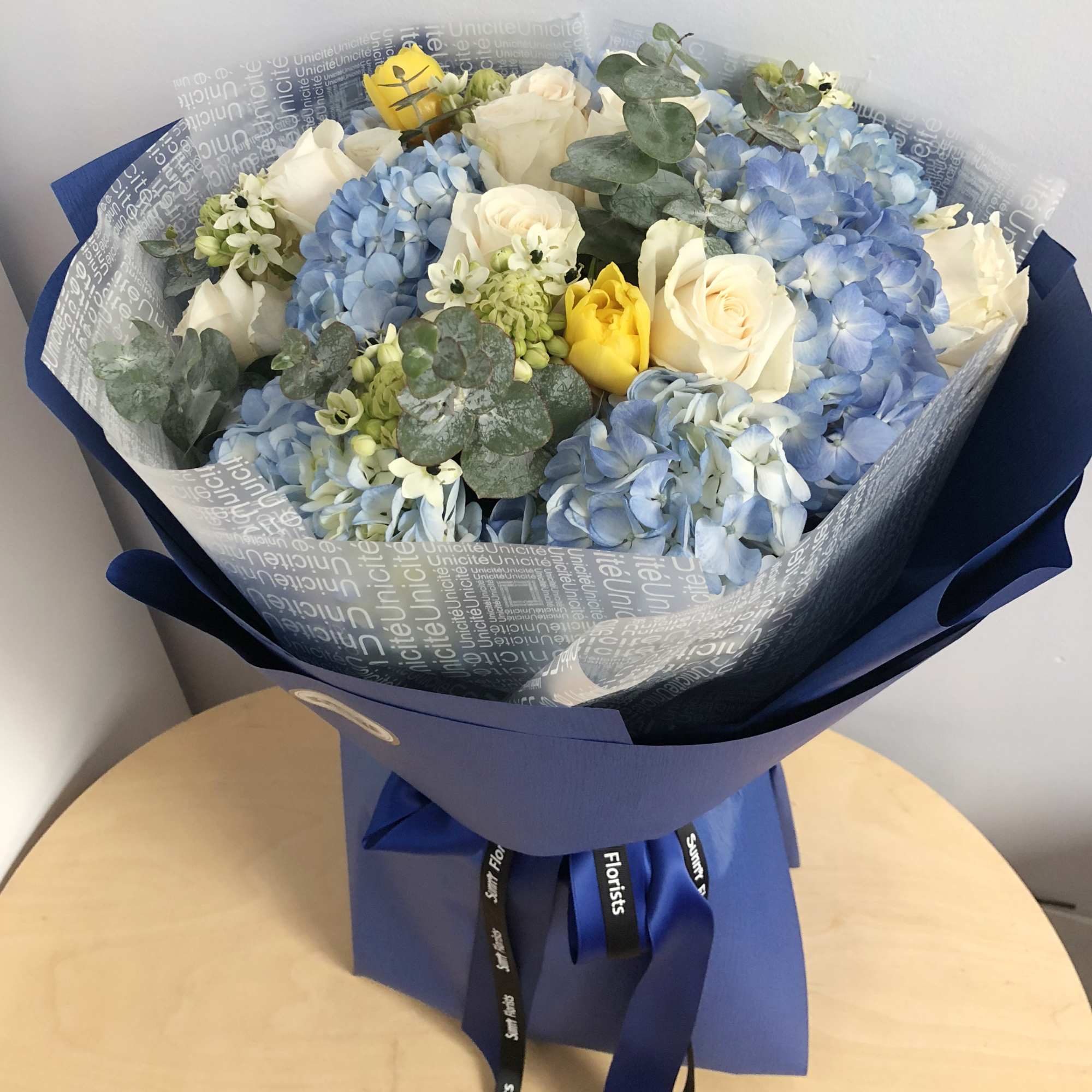 Bouquet of blue hydrangeas and white roses with yellow accents