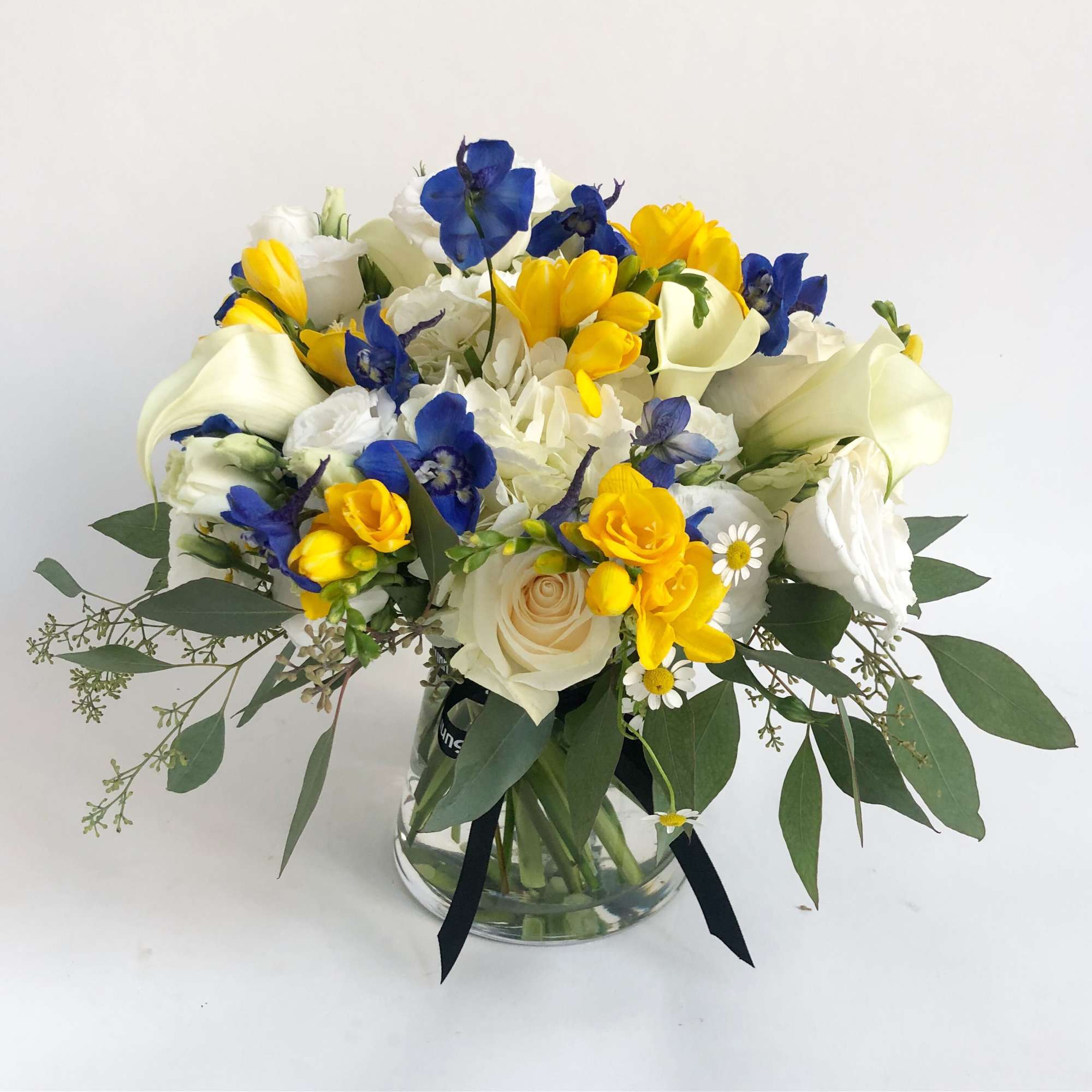 Bouquet of blue, yellow, and white flowers in a glass vase