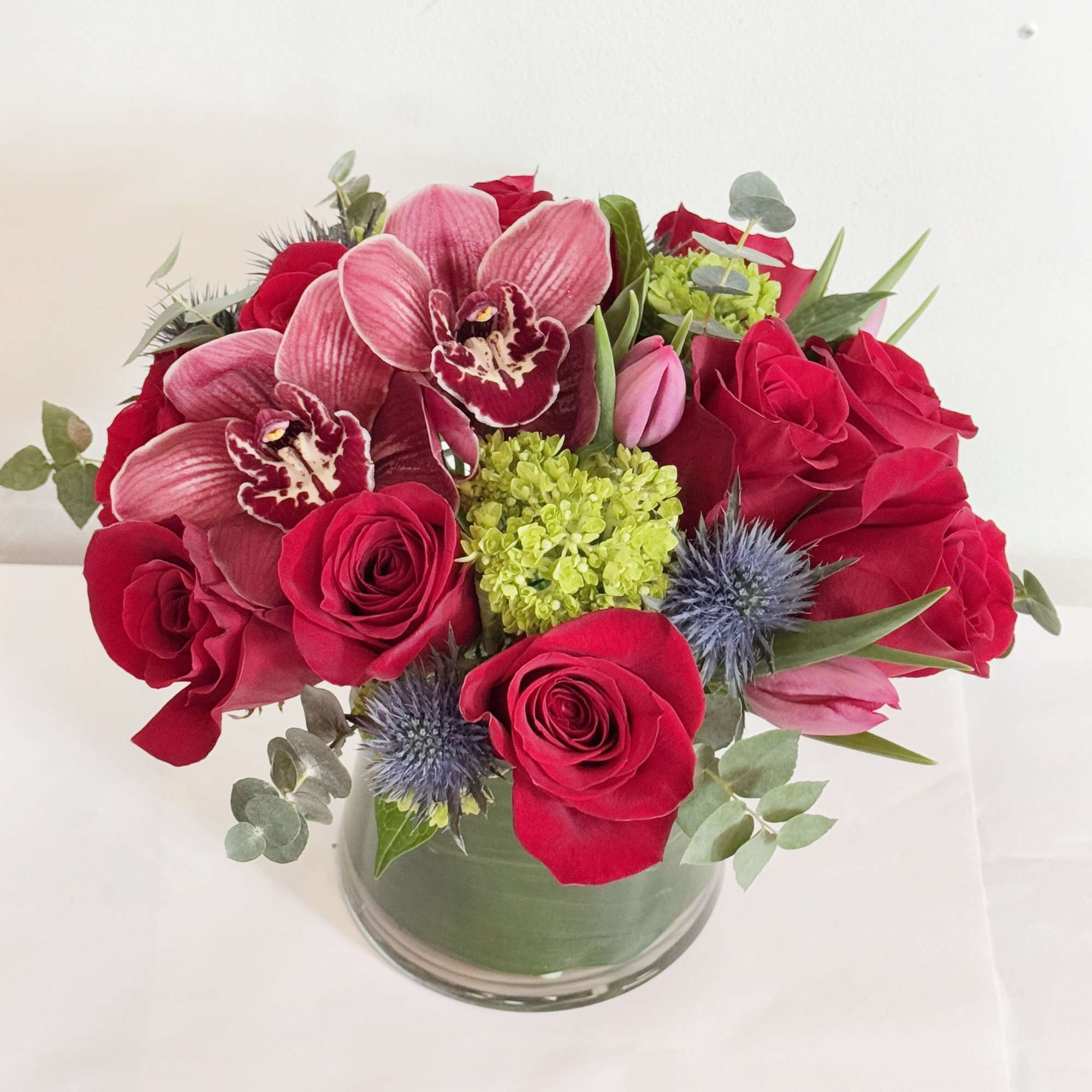 Bouquet of red roses and pink orchids in a glass vase