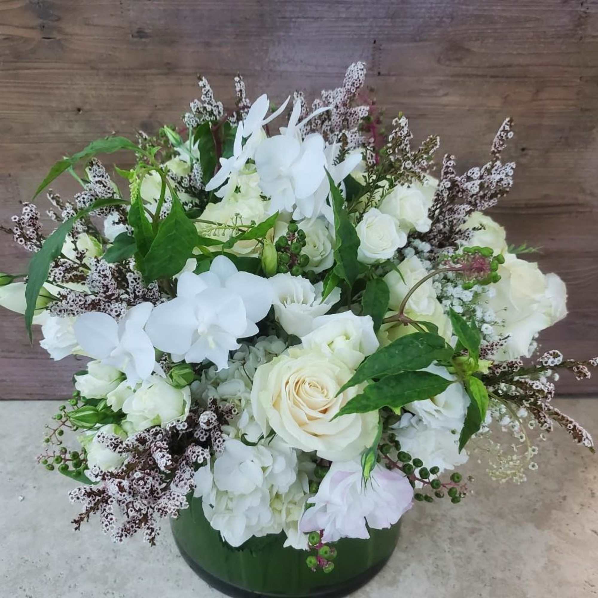 White roses and orchids arranged in a green vase