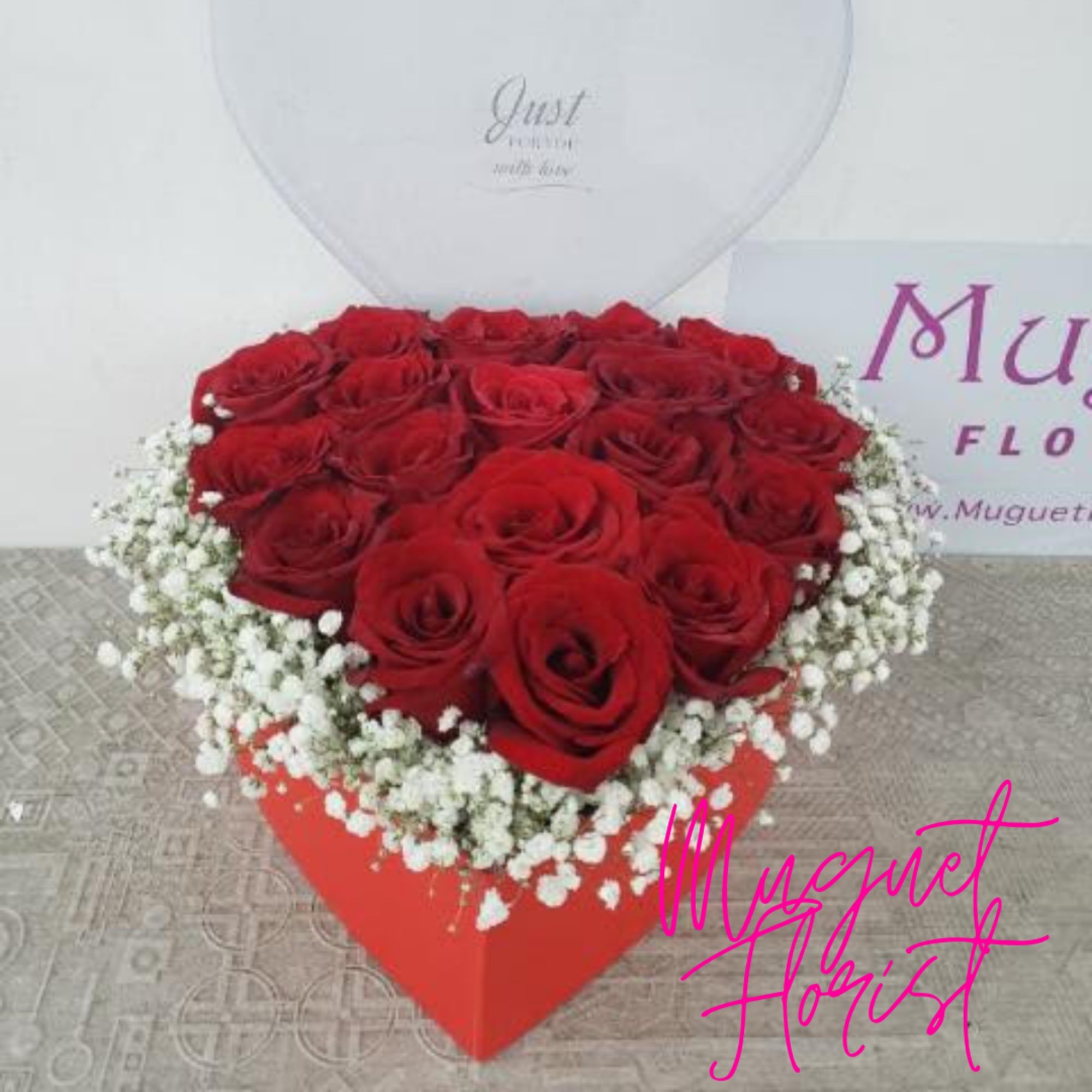 Heart-shaped box filled with red roses and white baby's breath