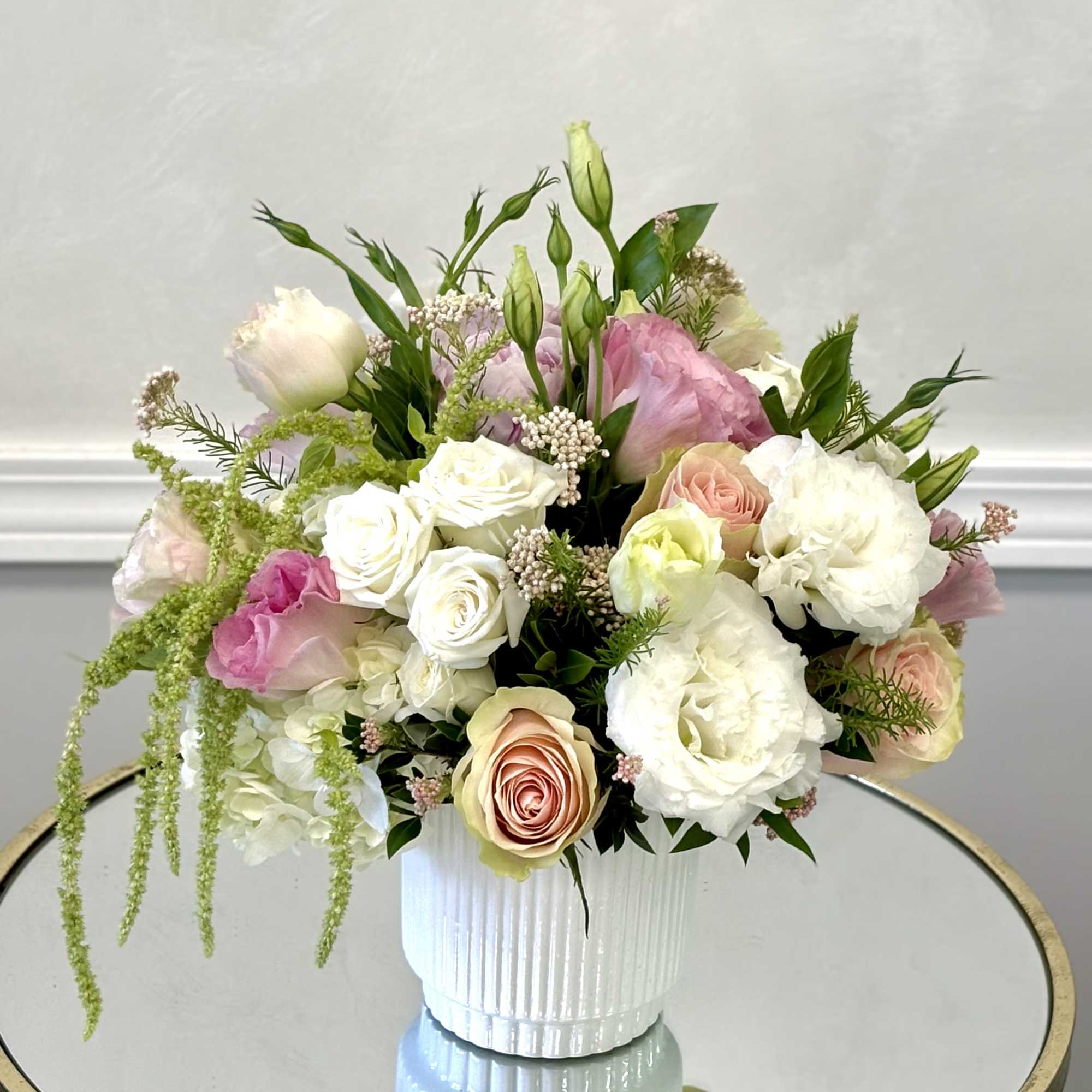 Blush tones and creamy whites blend beautifully with lush greenery, creating a