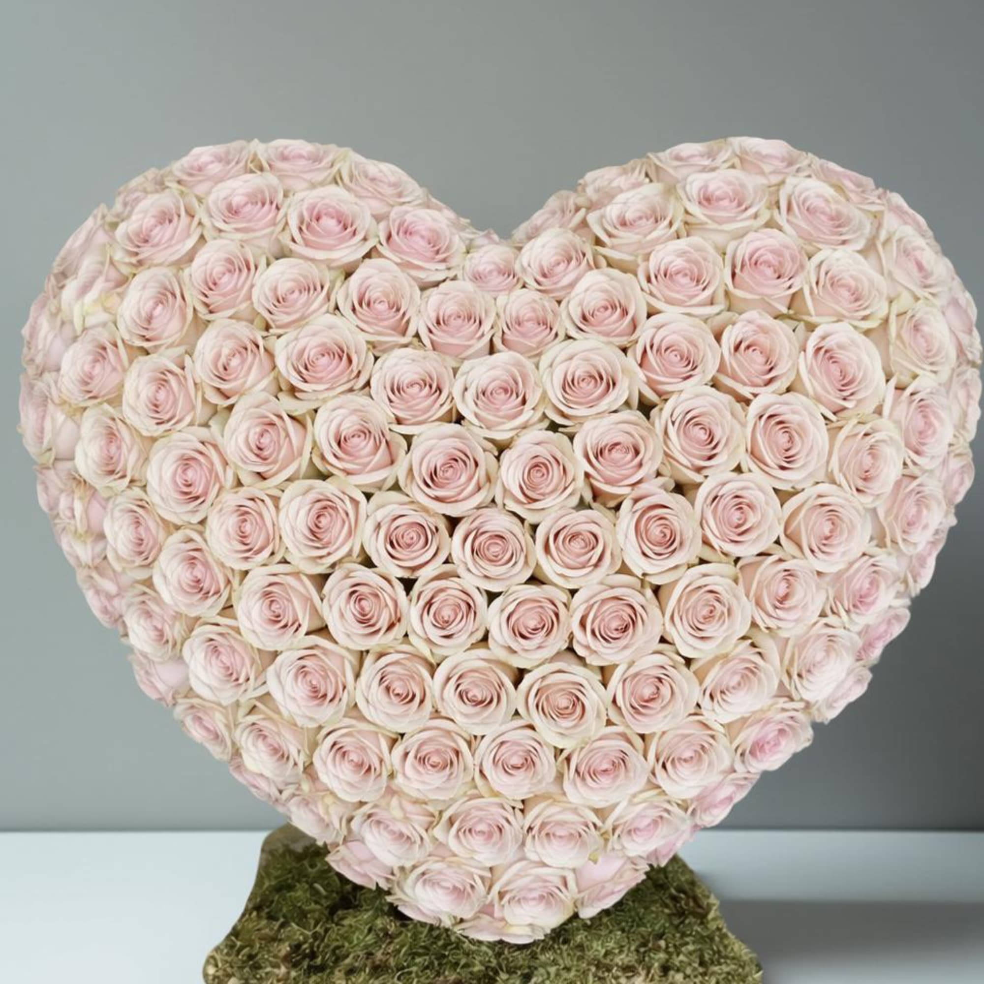 Heart-shaped arrangement of pale pink roses on a moss base