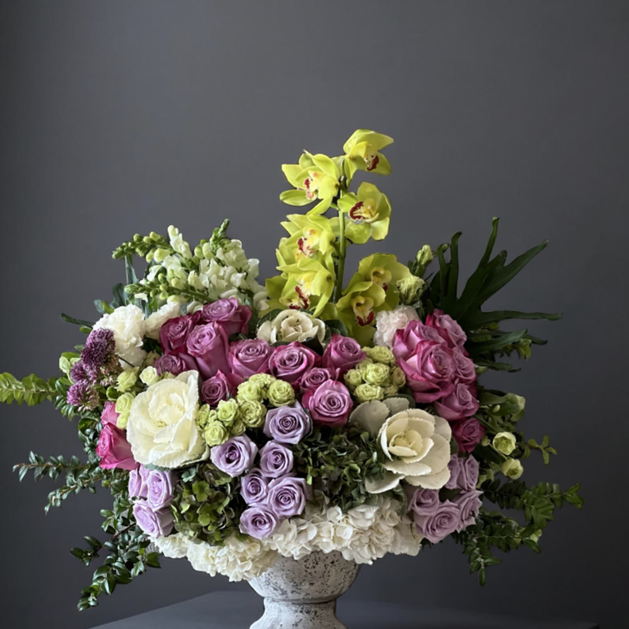 An elegant garden-style arrangement featuring soft lavender and purple  roses, creamy