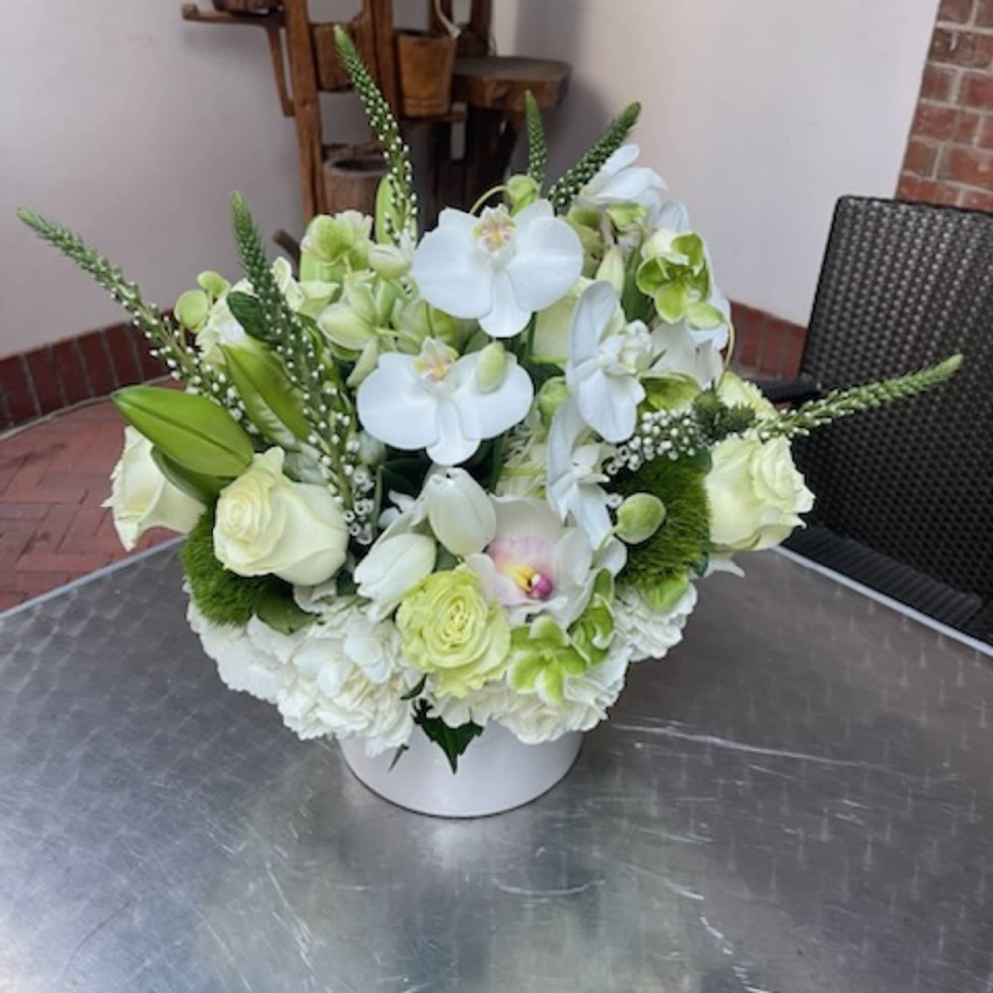 White and pale green floral arrangement in a white container