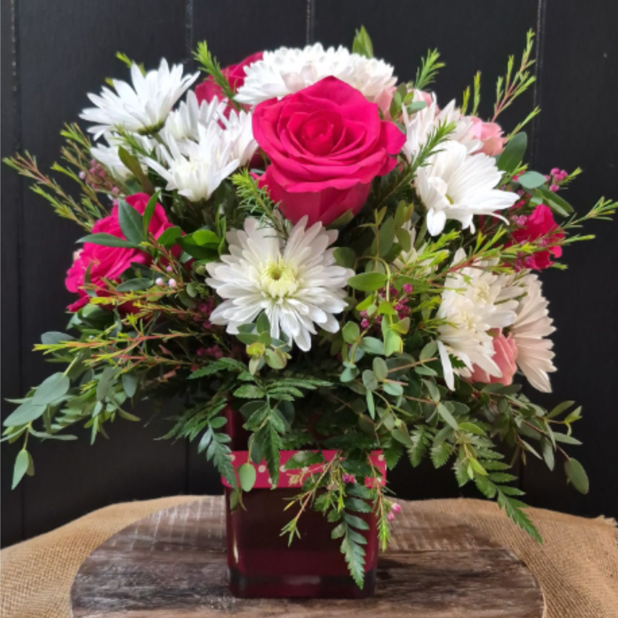 Hot pink roses, spray roses, and white daisies in a pink vase
