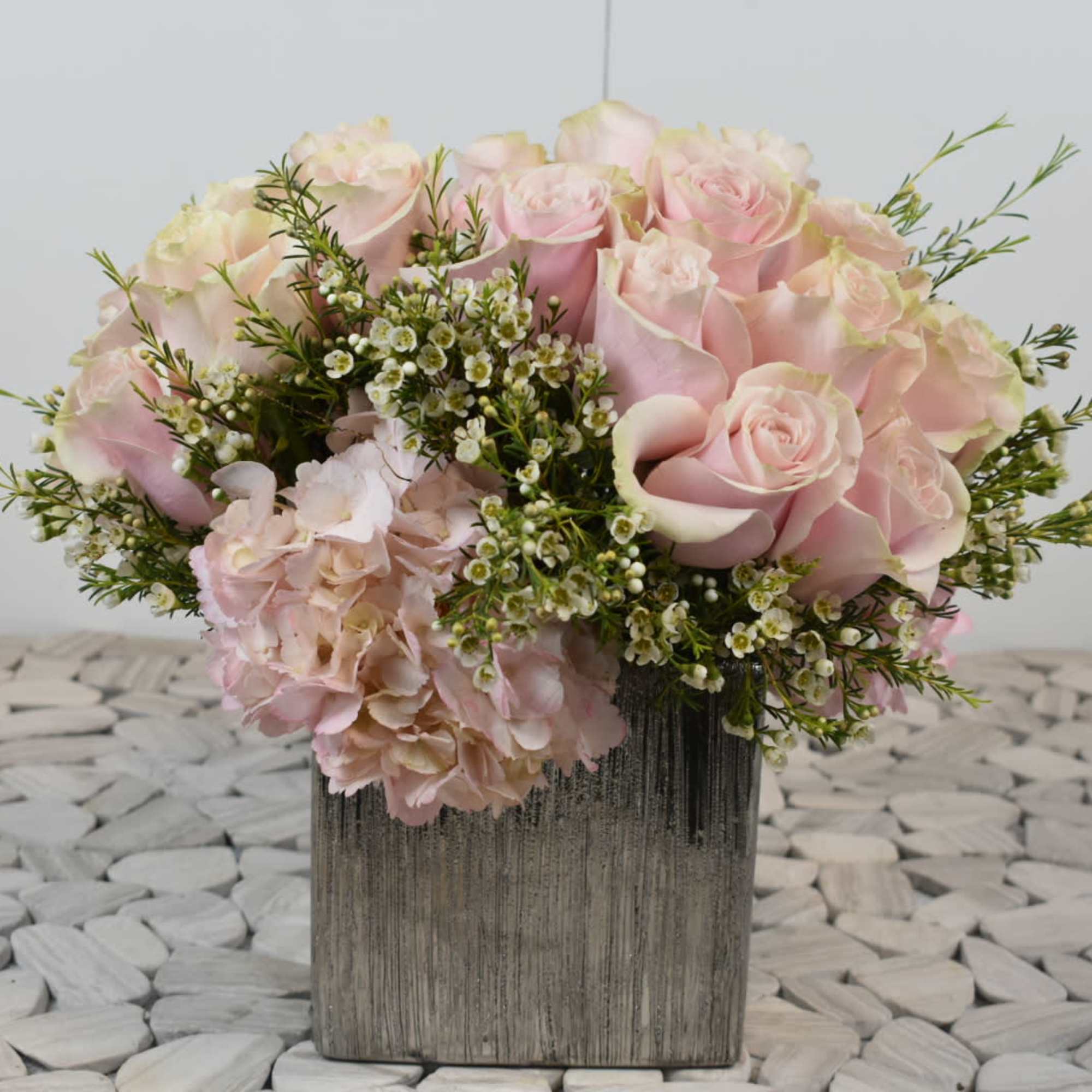 Pink roses and hydrangeas arranged in a square vase
