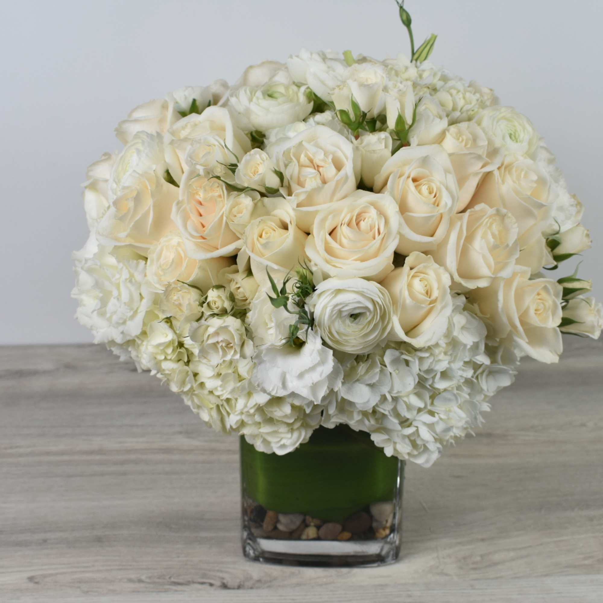 Cream rose bouquet in a square glass vase