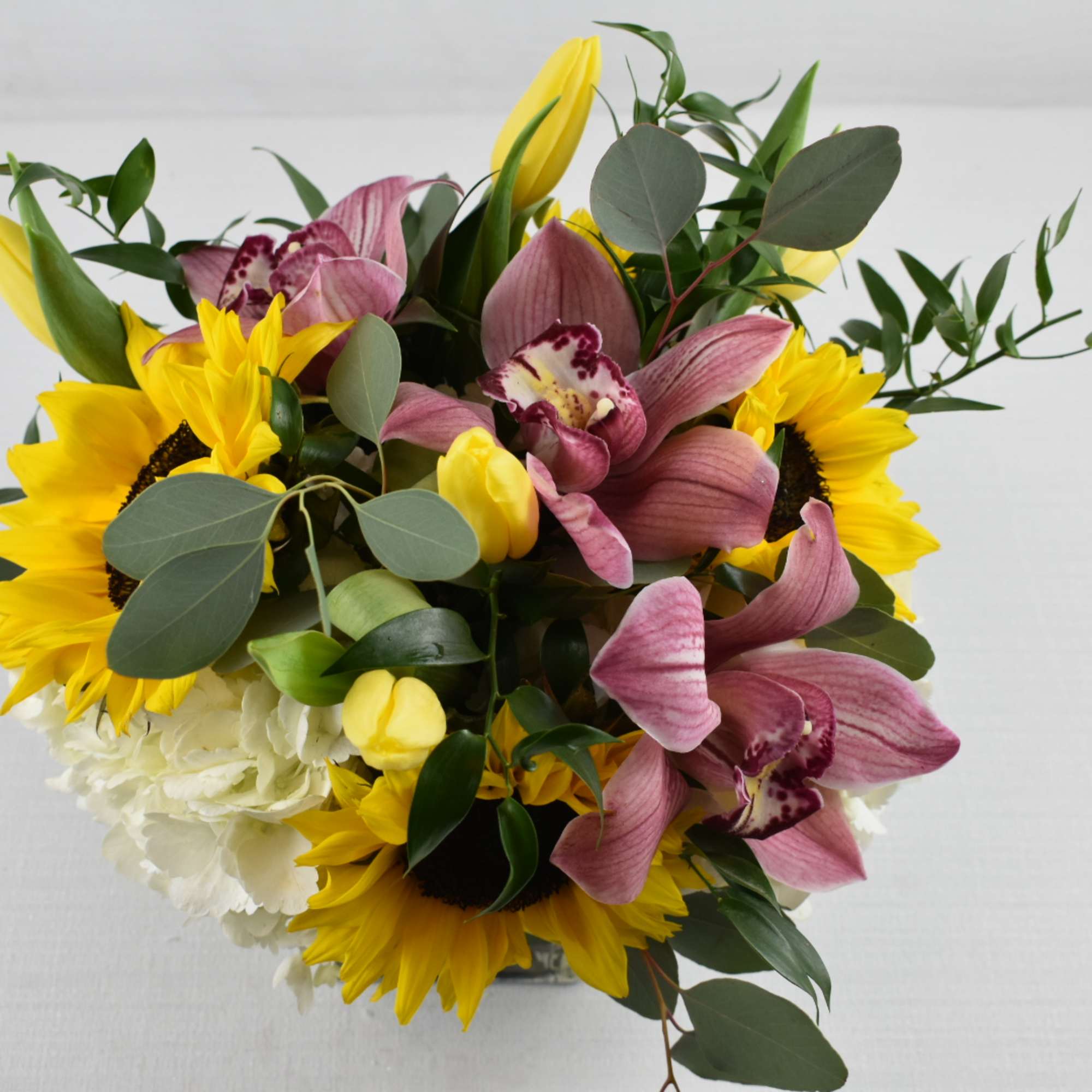 Bouquet of yellow sunflowers, pink orchids, and white hydrangeas