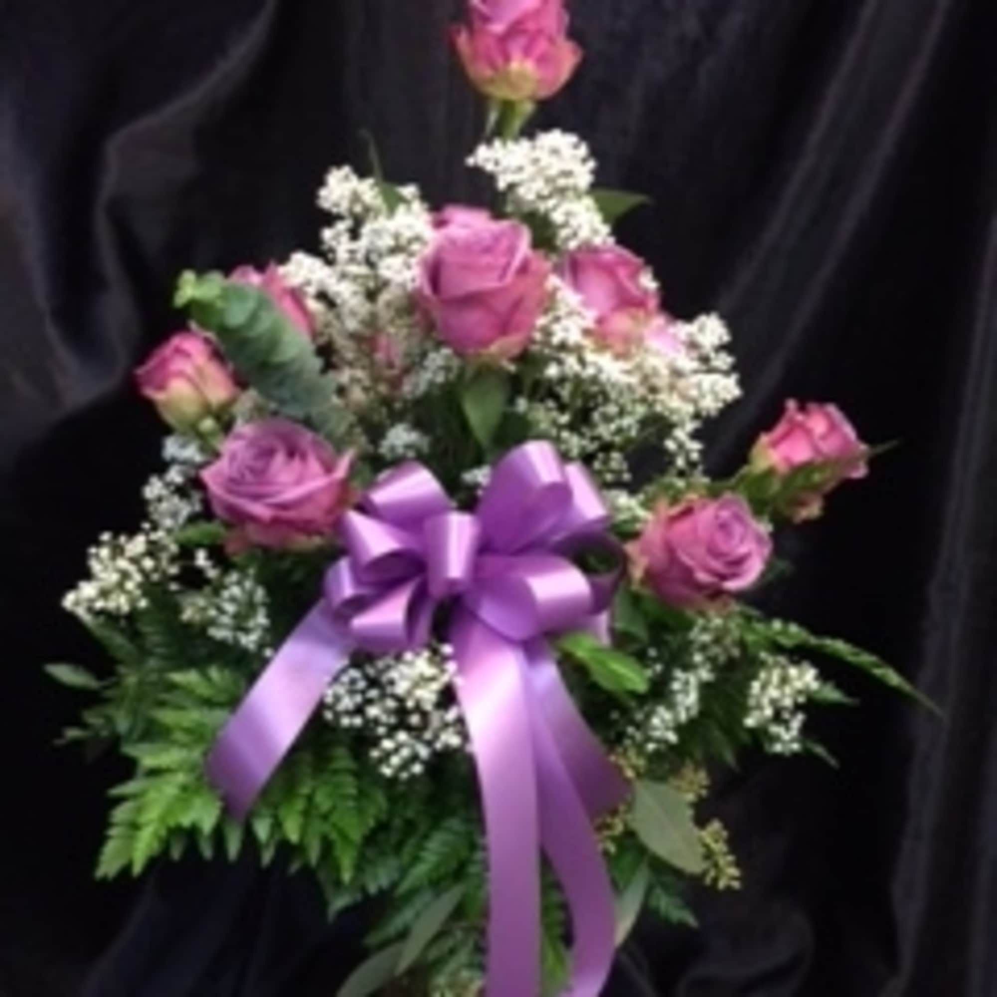 Pink rose bouquet with white filler flowers and a purple ribbon