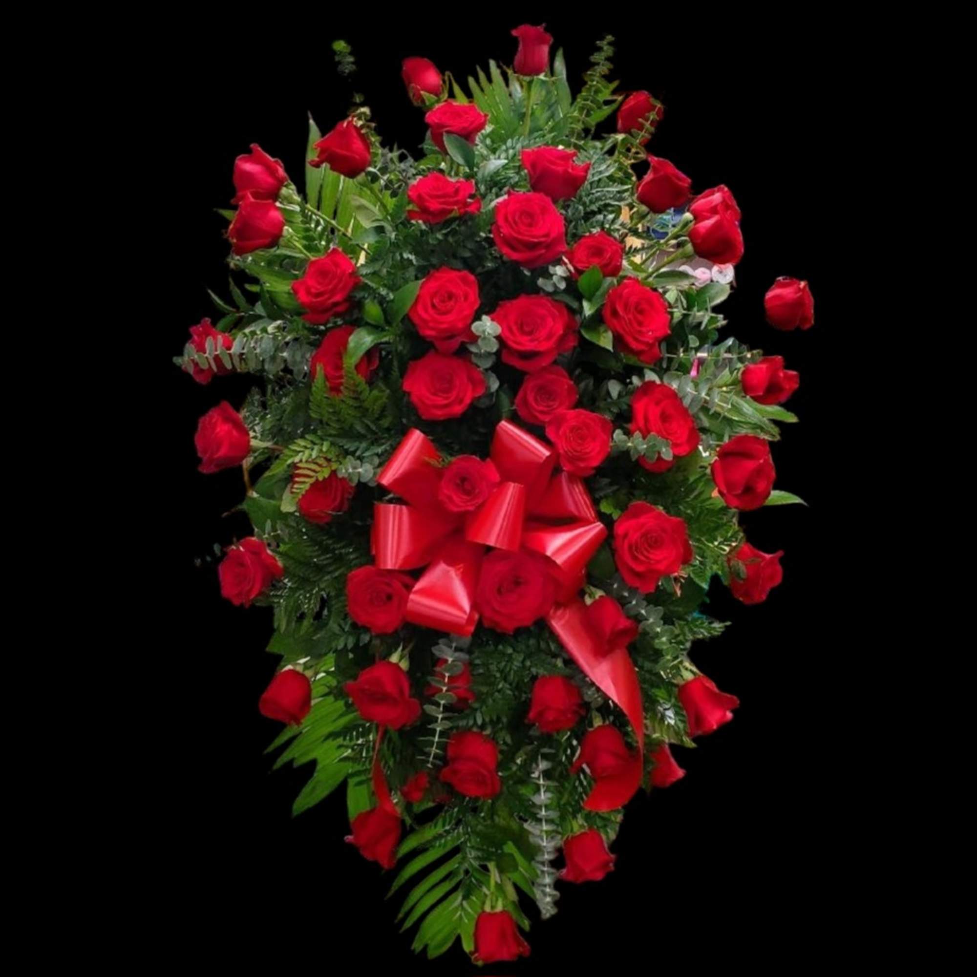 Heart-shaped arrangement of red roses with a red ribbon on a black background