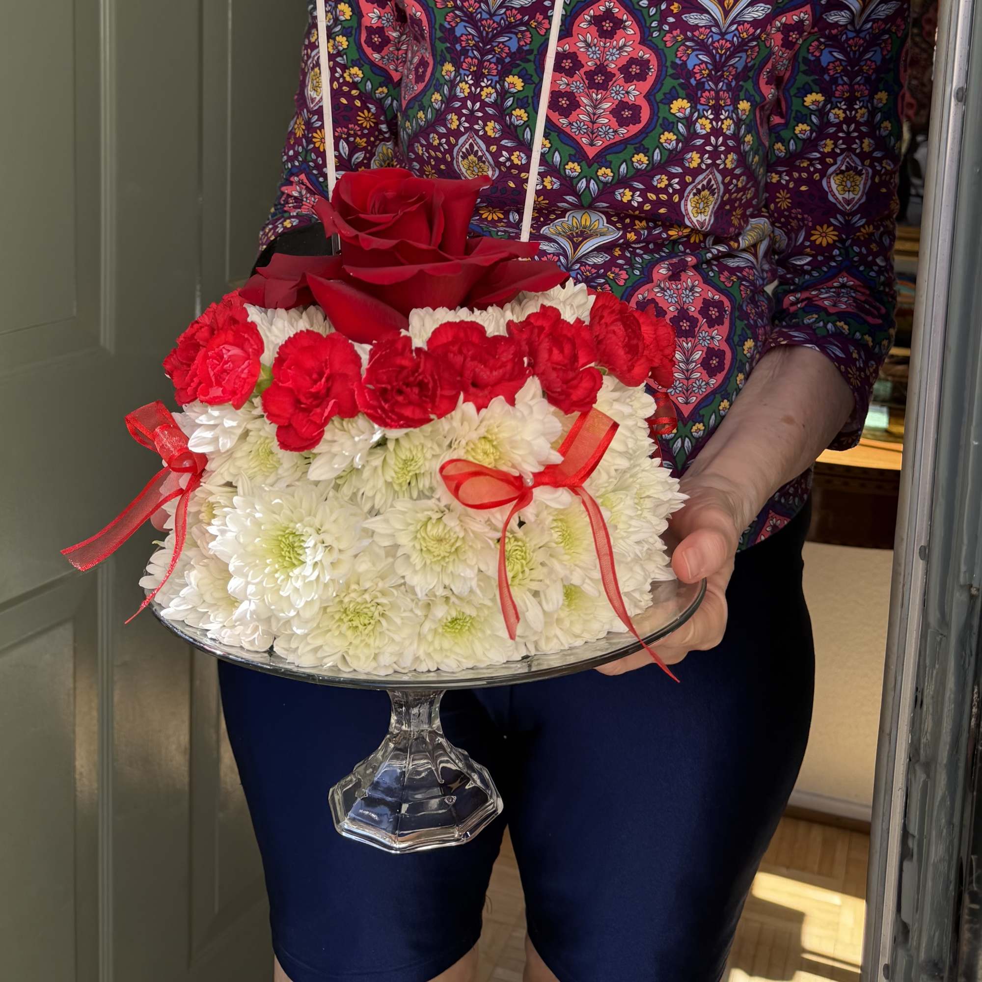 Red roses and white chrysanthemums arranged on a glass pedestal stand