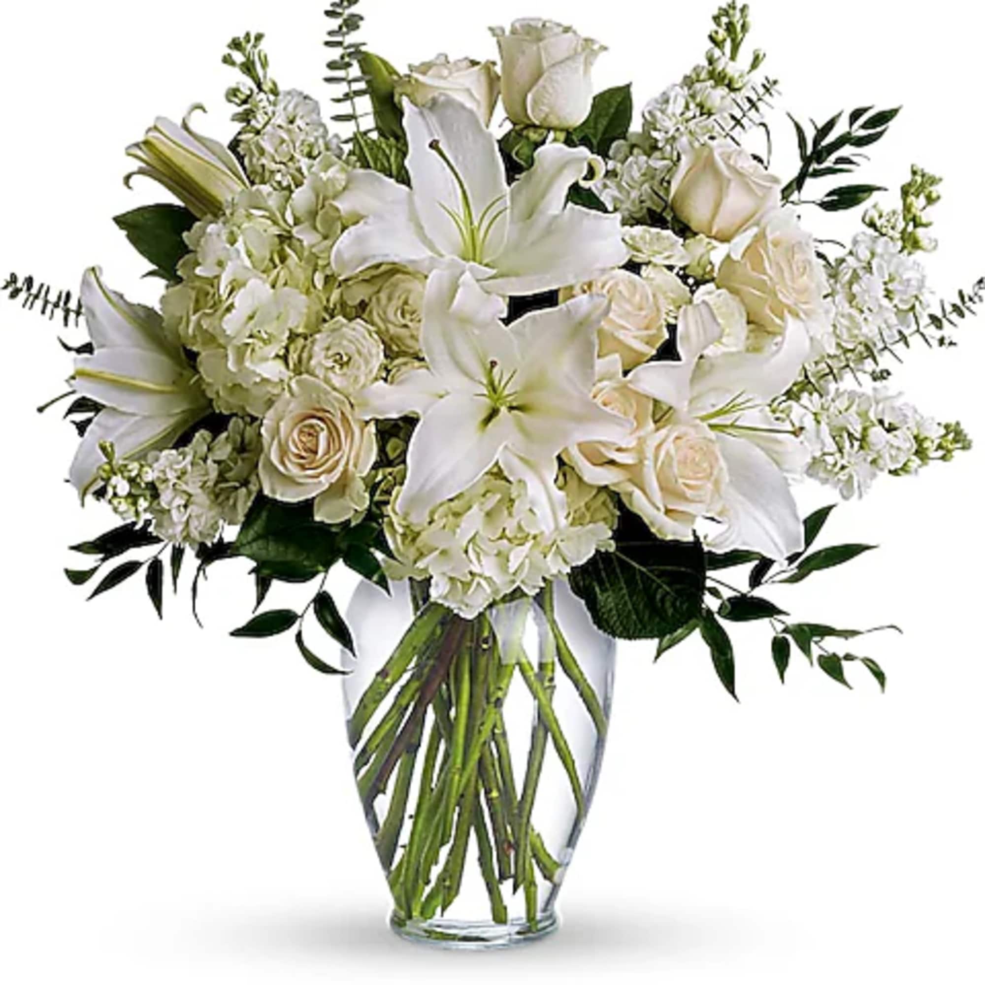 White lilies and roses arranged in a clear glass vase