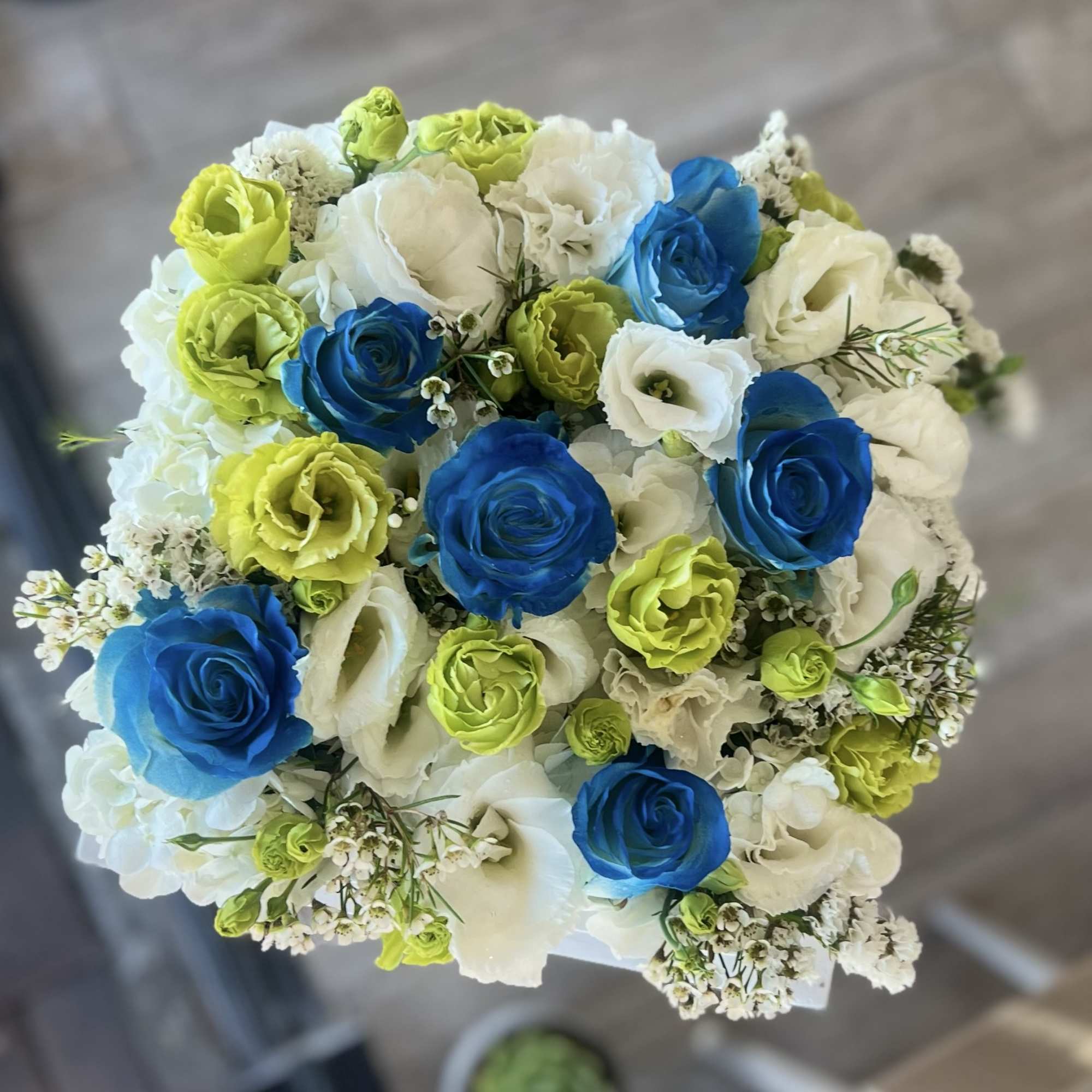 Round bouquet of blue, white, and lime flowers