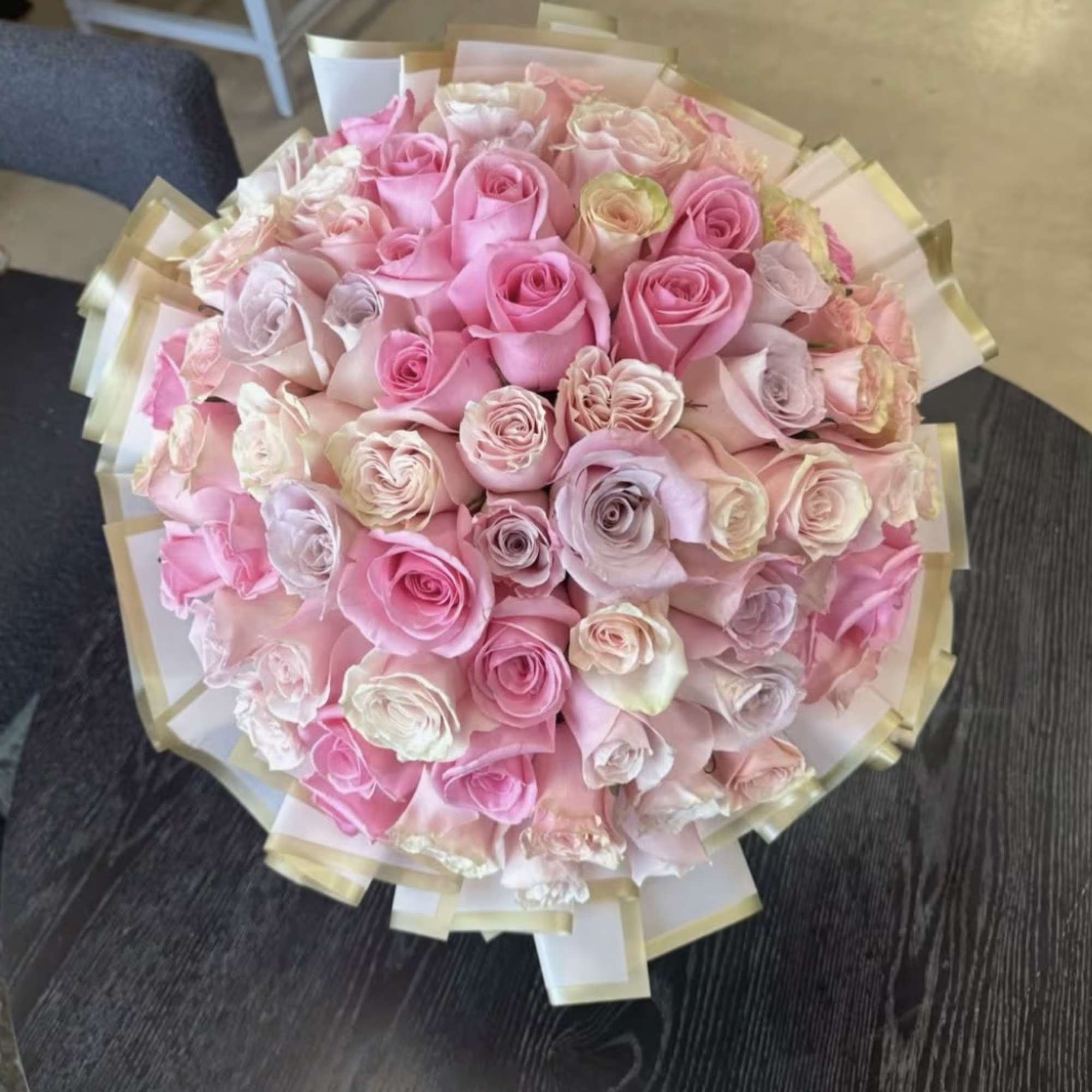 Large bouquet of pink and blush roses wrapped in pale paper
