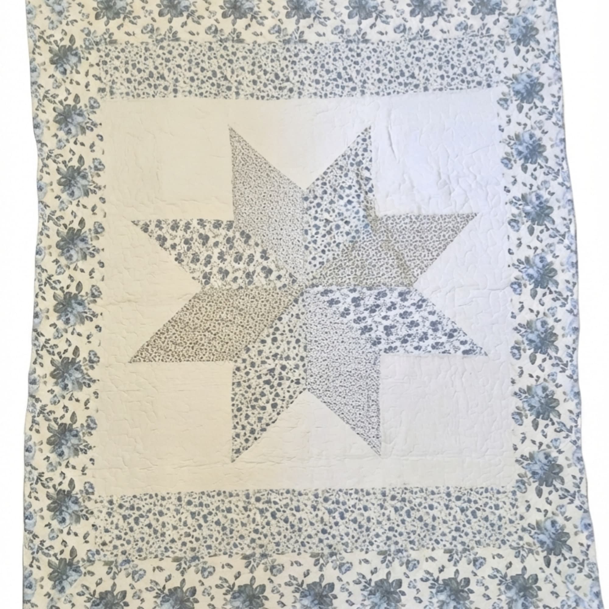 Patchwork quilt with a large star pattern and blue floral border