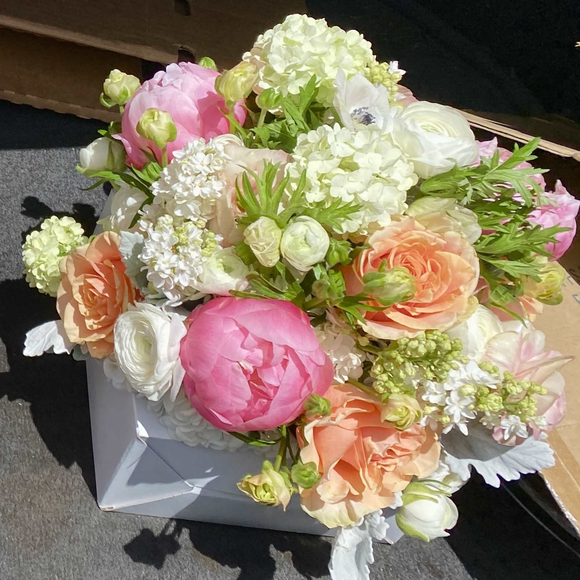 Bouquet of pink, peach, and white flowers in a white box