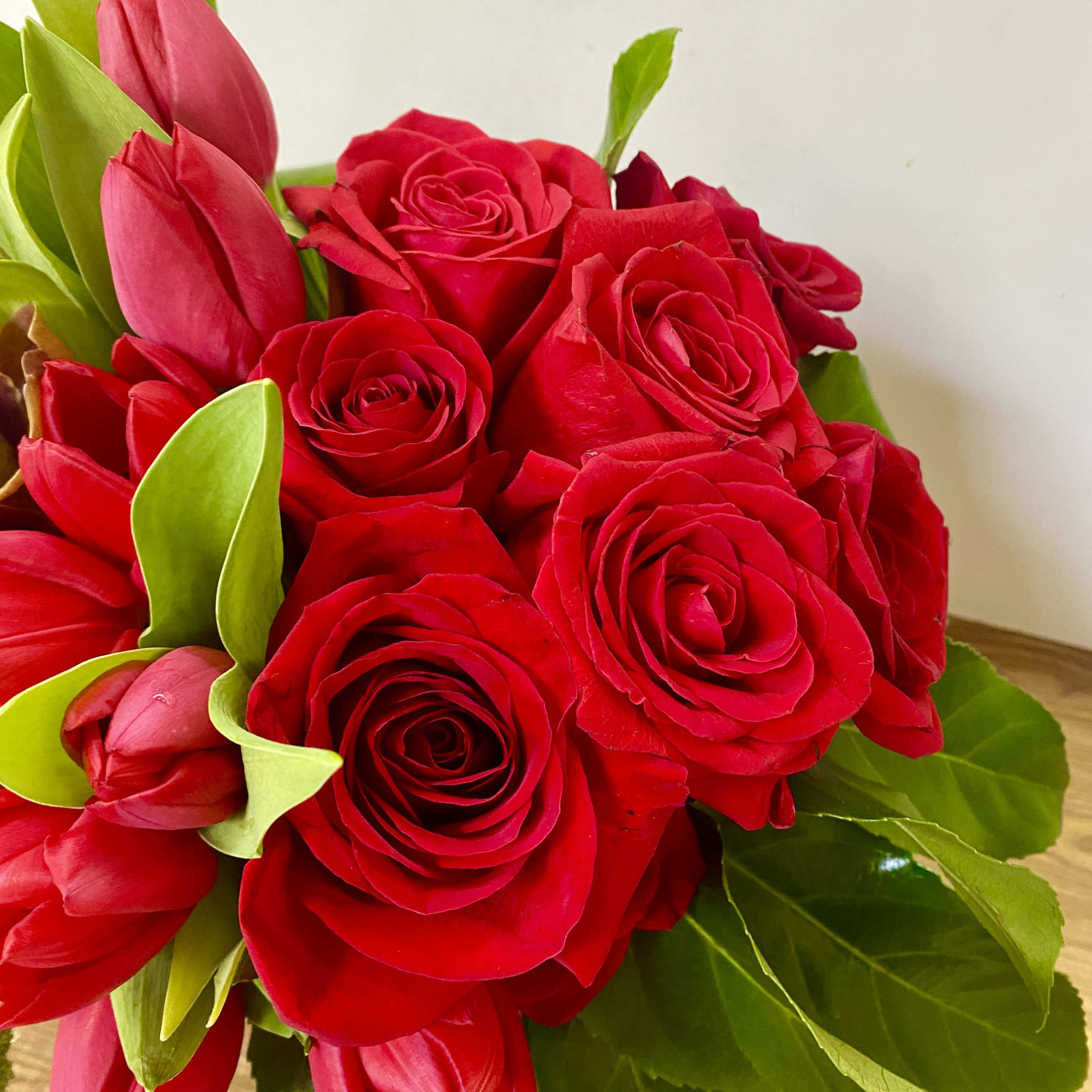 Bouquet of red roses and red tulips with green leaves