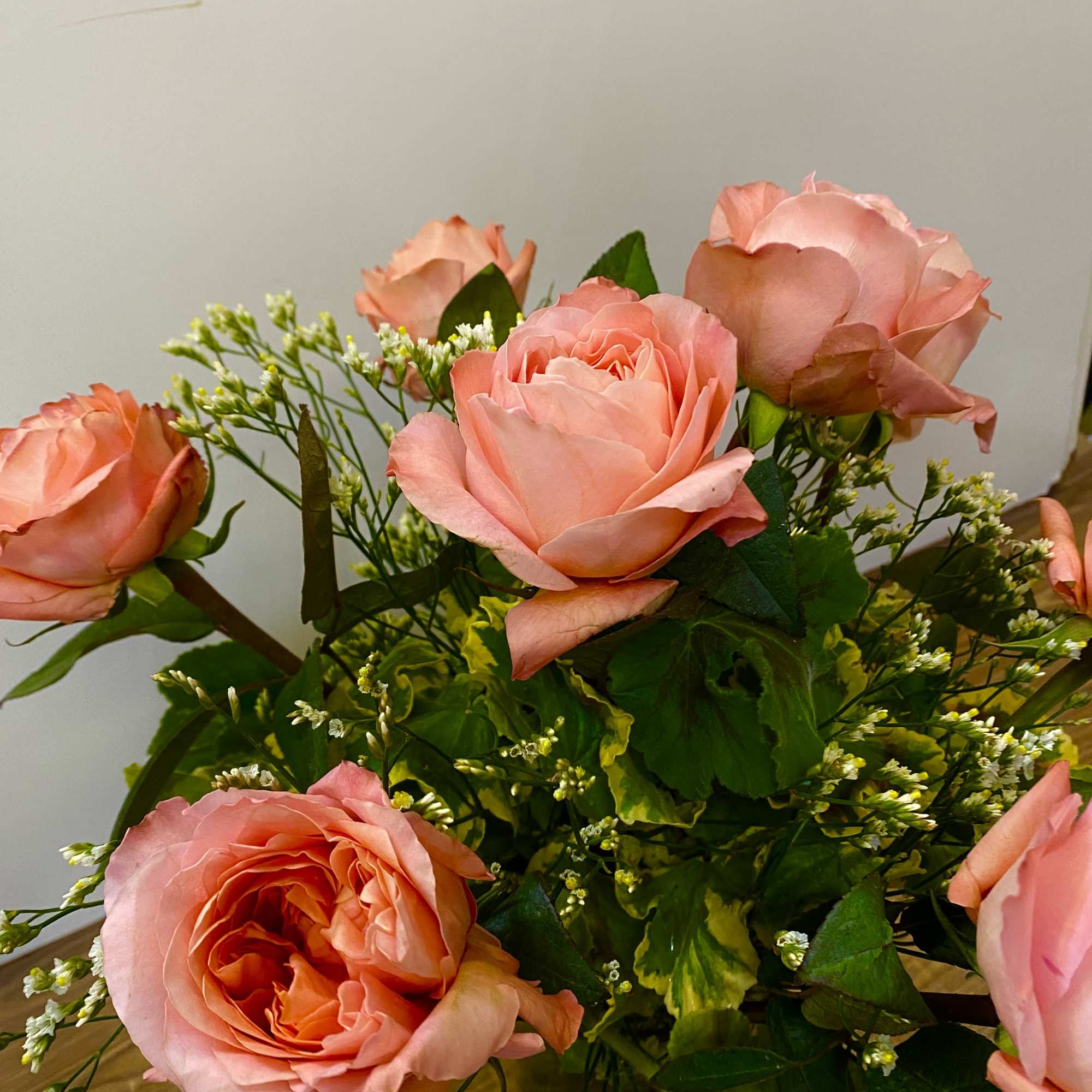 Bouquet of peach-pink roses with small white filler flowers, photo 4 of 5