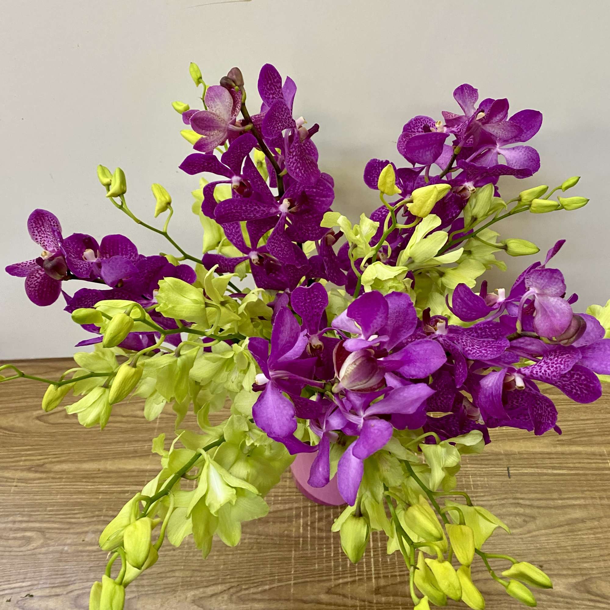 Purple and lime orchid arrangement in a pink vase, photo 3 of 3
