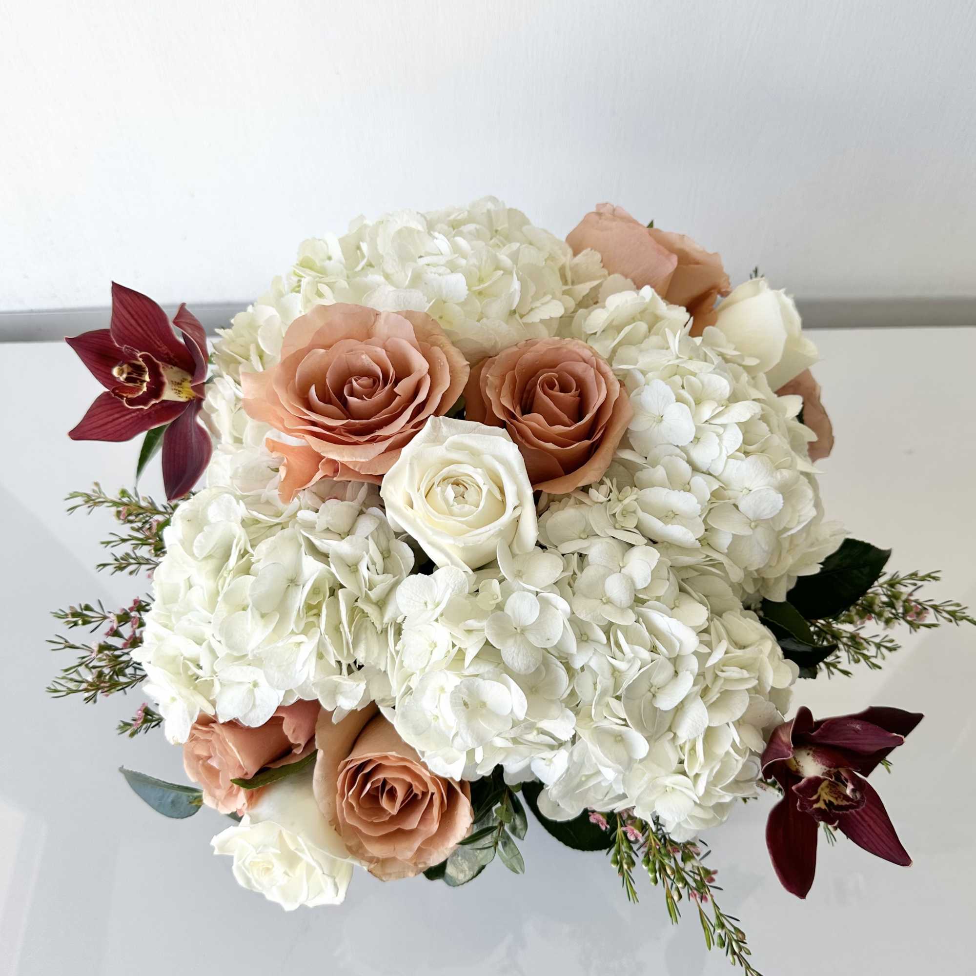 Peach roses and white hydrangeas with burgundy orchids in a bouquet