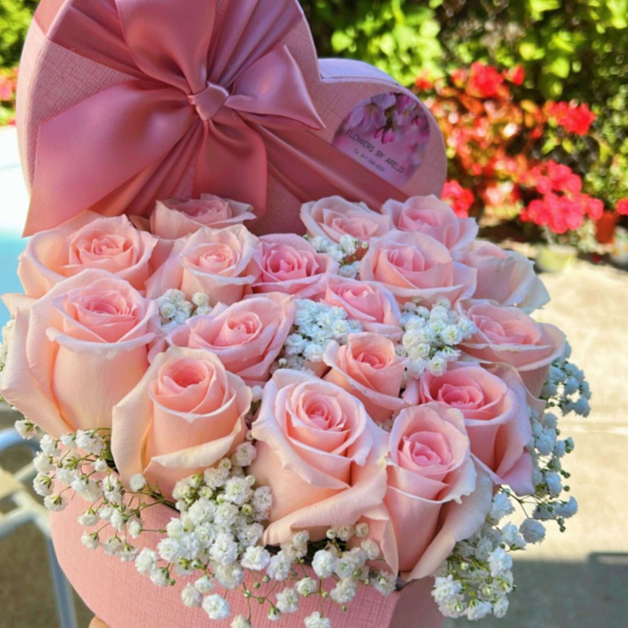 Pink roses arranged in a heart-shaped box with a satin bow