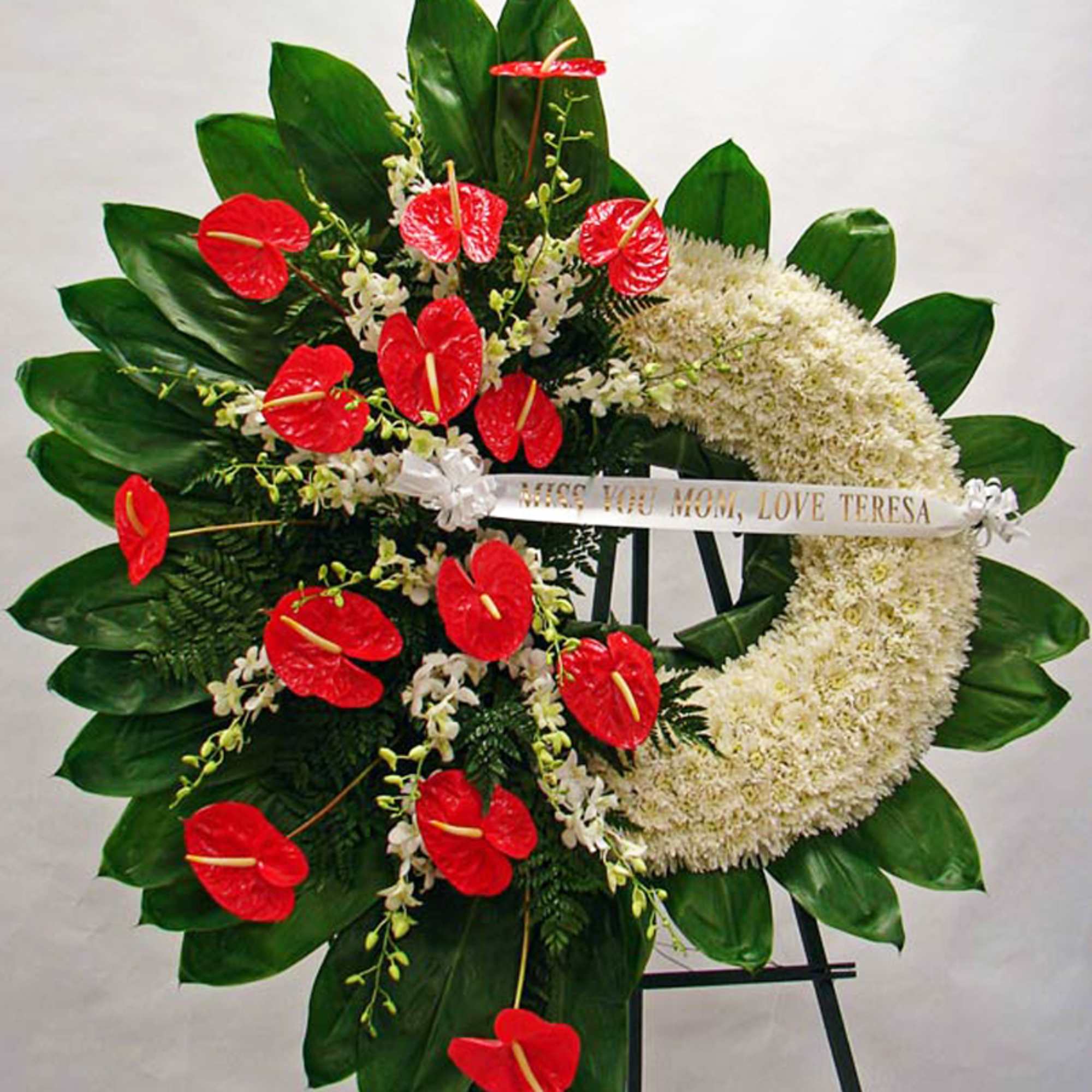 Crescent white wreath with red tropical blooms on a standing easel