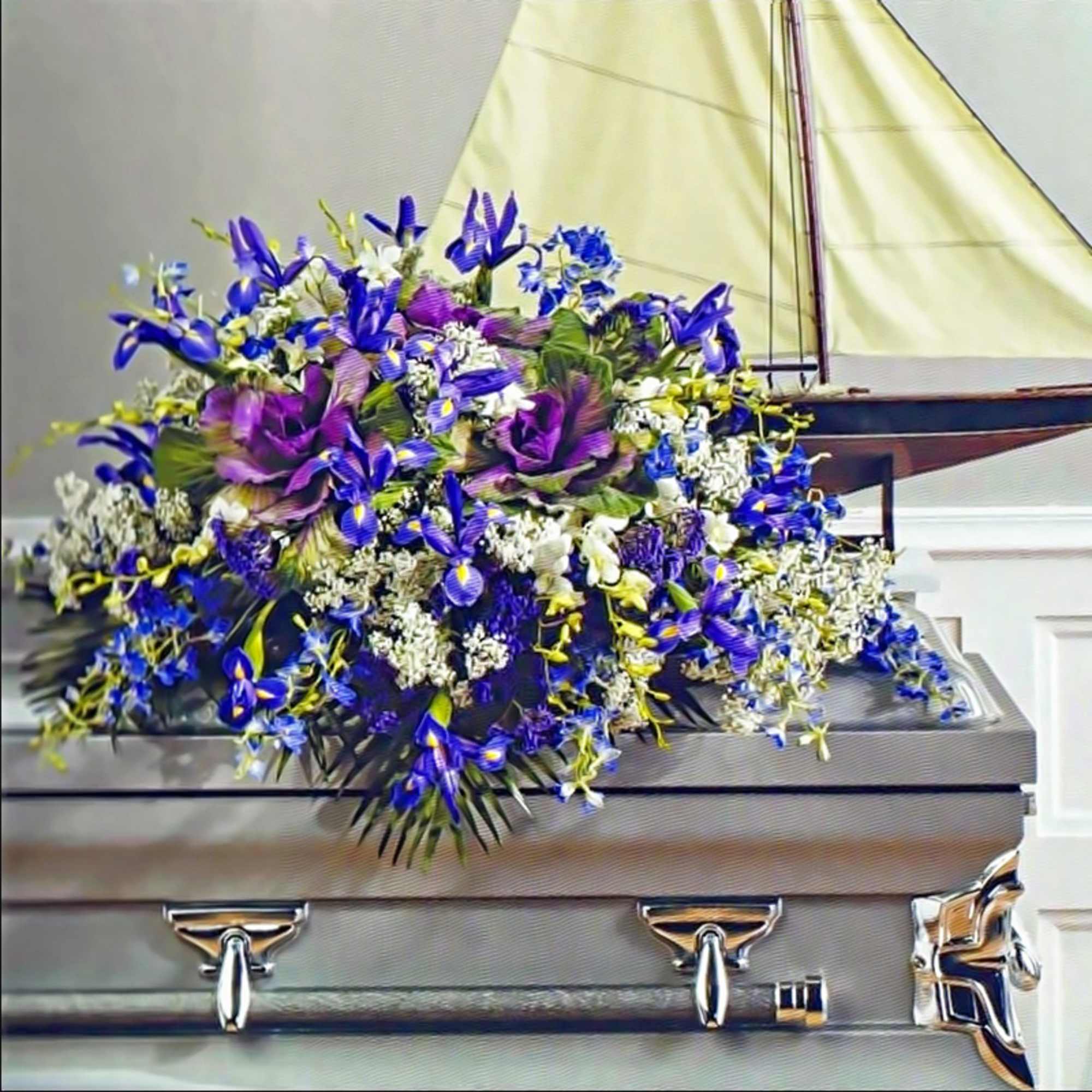 Purple and blue casket spray arrangement displayed on a silver casket.