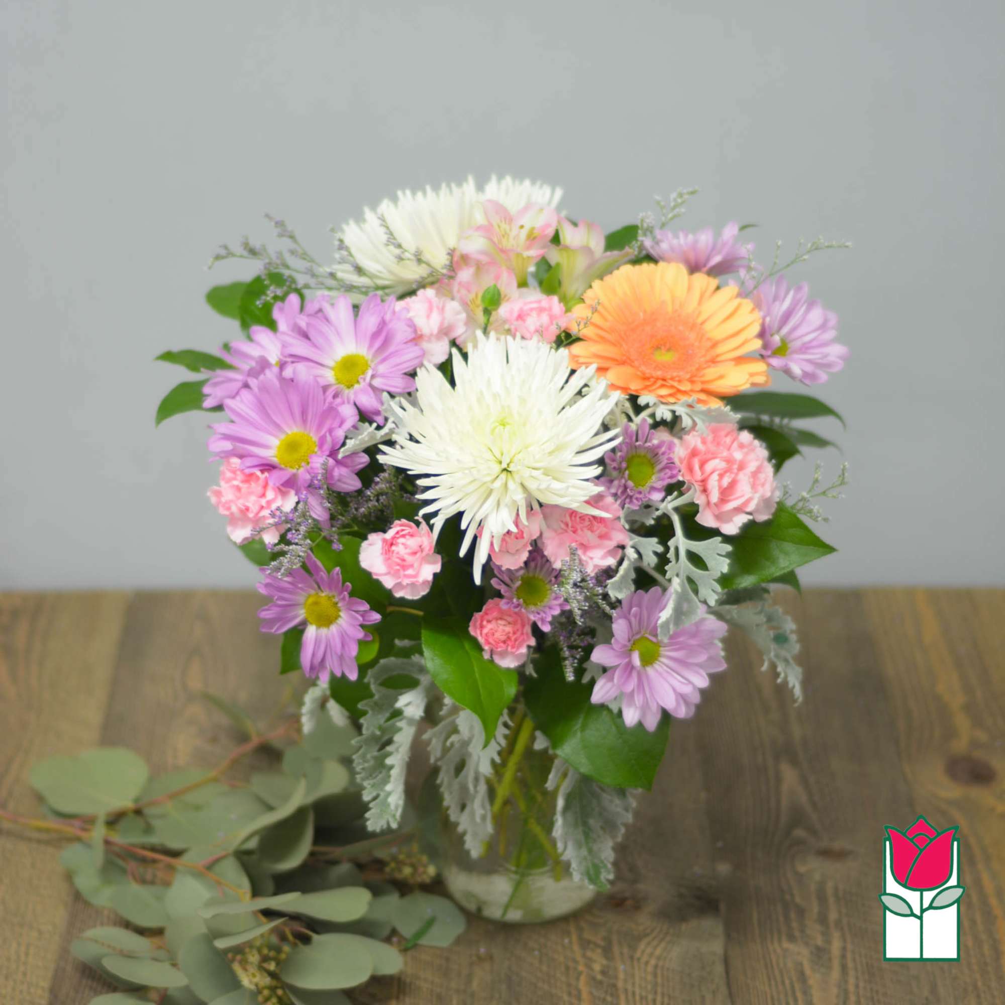 Mixed bouquet of daisies, carnations, and gerbera daisies in a glass vase