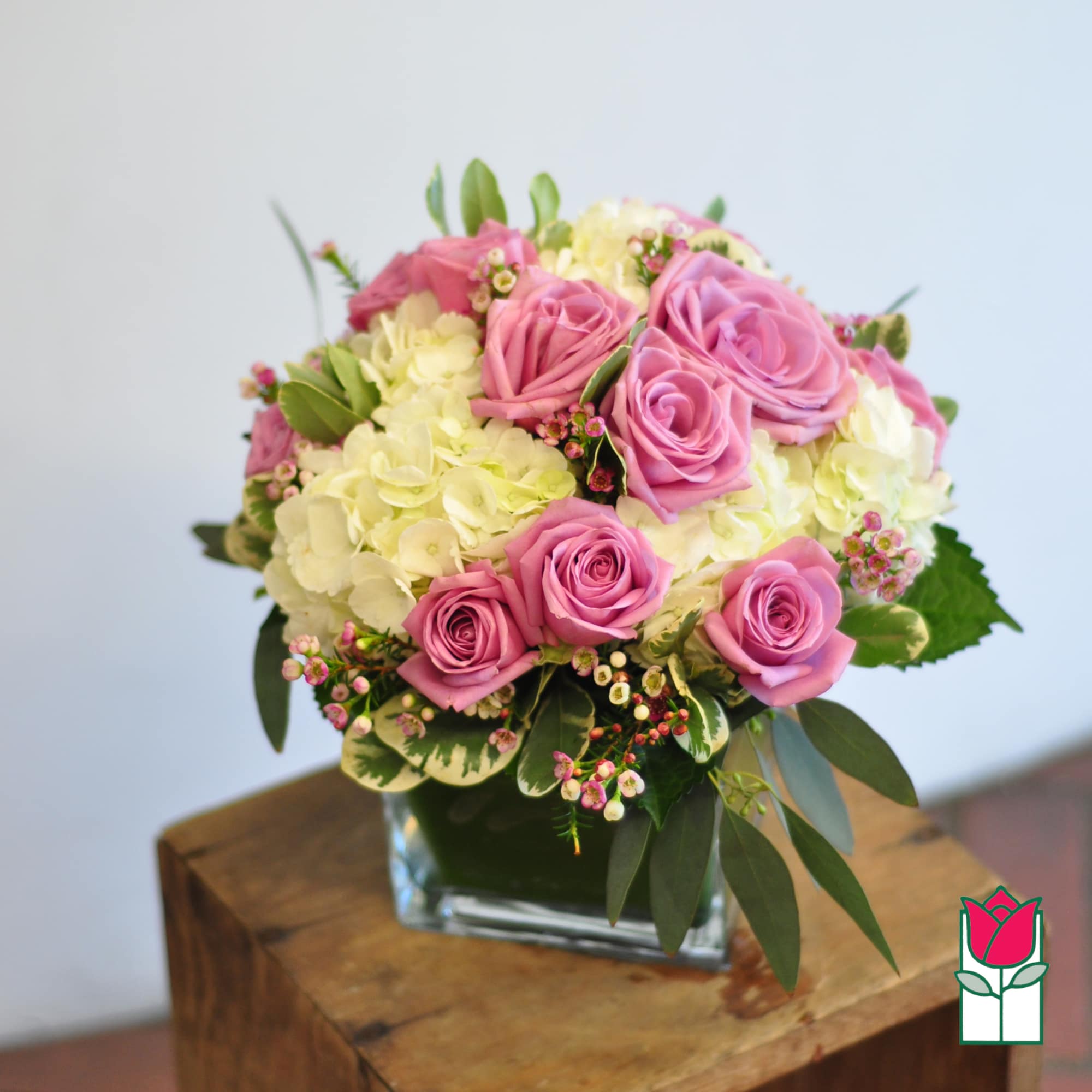 Pink roses and pale hydrangeas in a square glass vase