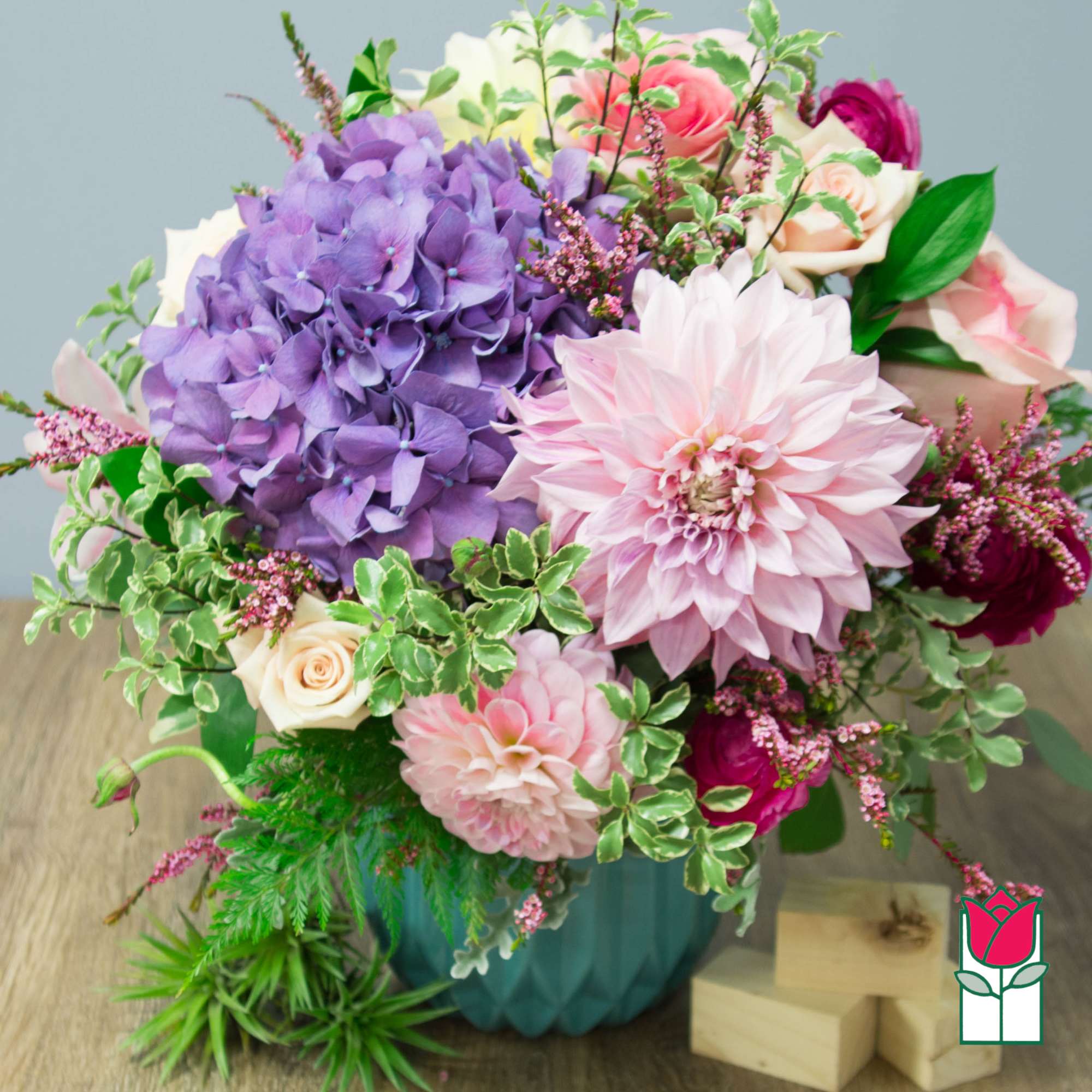 Bouquet of purple hydrangea, pink dahlias, and roses in a teal vase