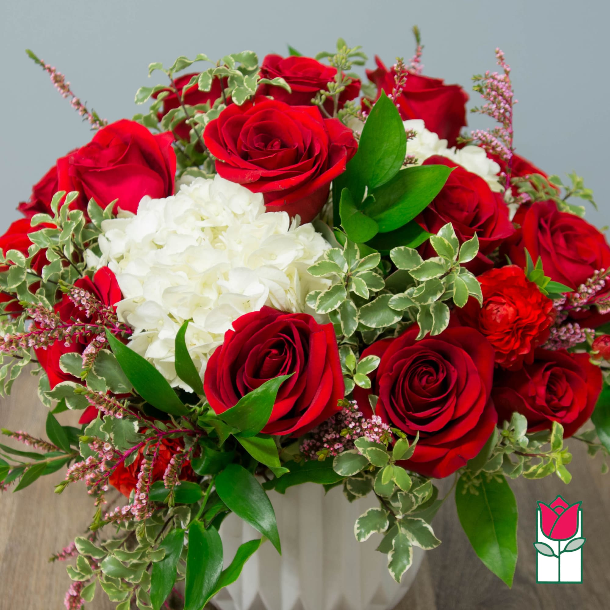 Red roses and white hydrangeas in a white vase