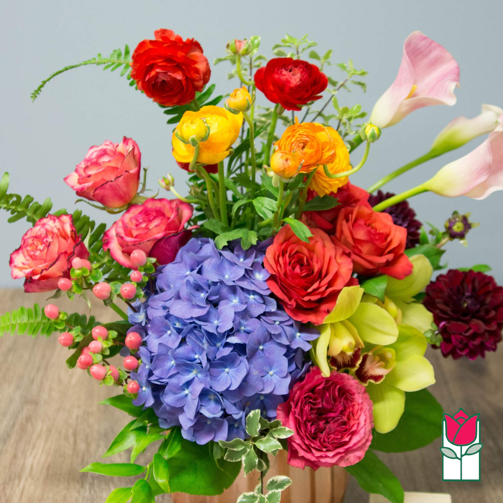 Colorful bouquet with hydrangea, roses, calla lilies, and ranunculus in a vase