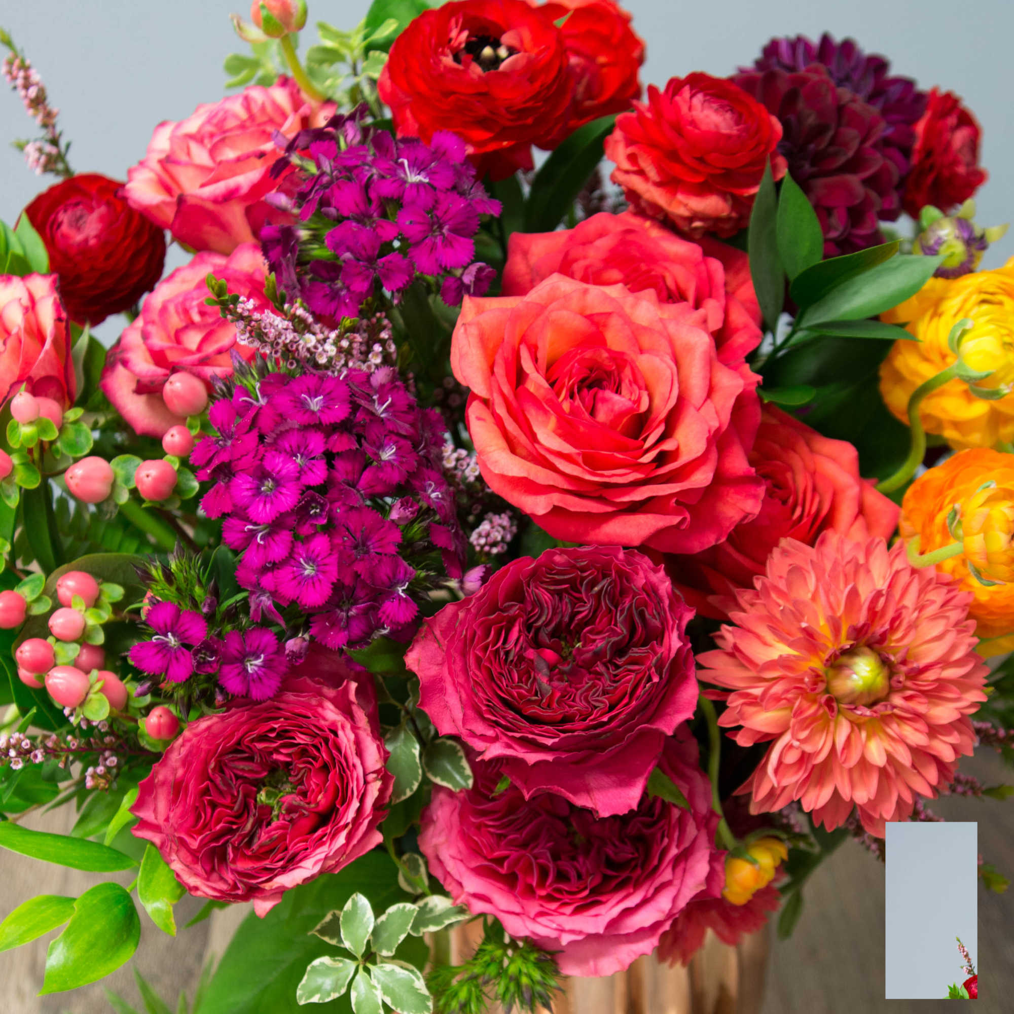 Mixed bouquet of roses, carnations, and dahlias in bright pink, red, and orange