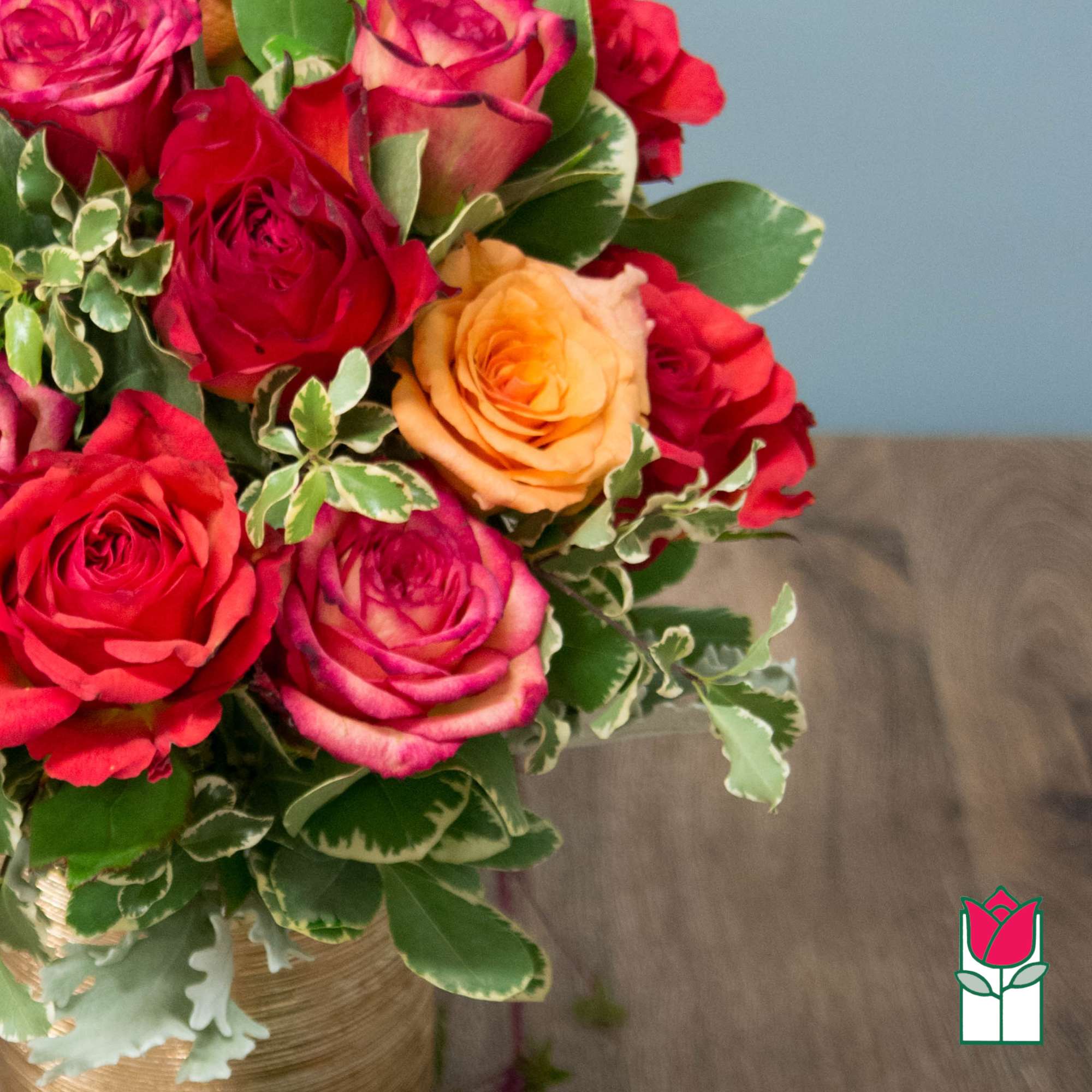 Bouquet of red, pink, and peach roses with variegated greenery