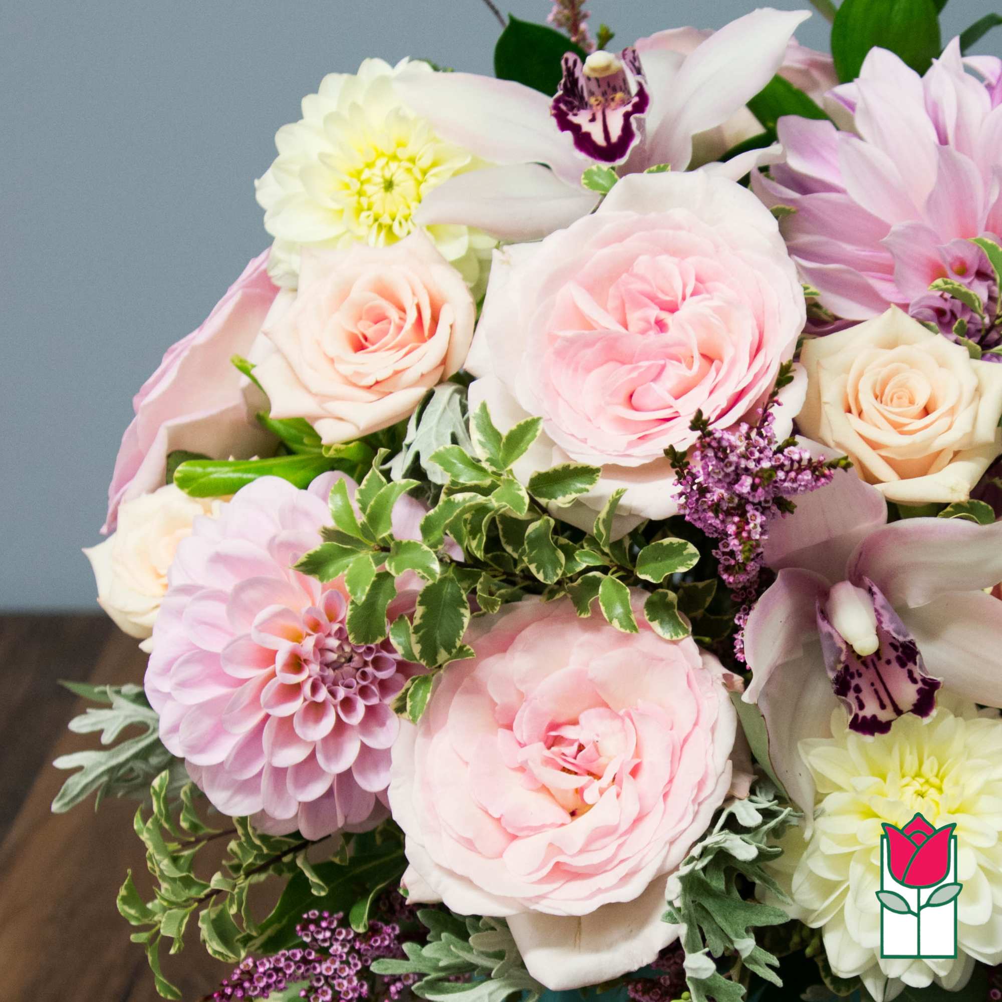 Bouquet of pink and cream roses with pale dahlias and orchids