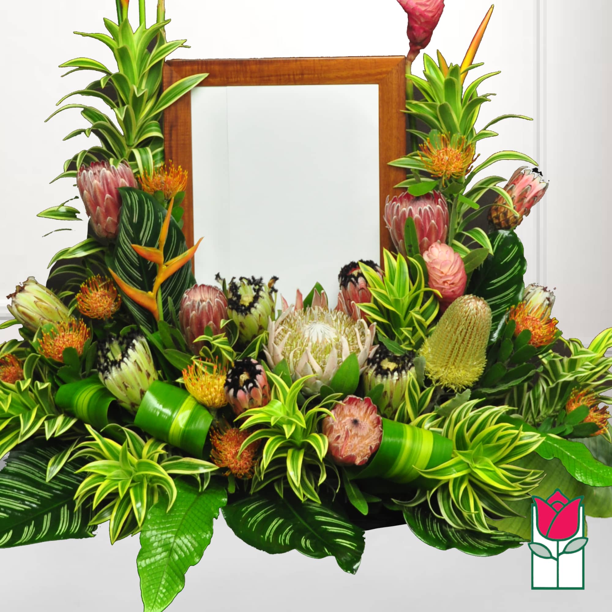 Tropical floral arrangement with protea and orange accents around a wooden frame