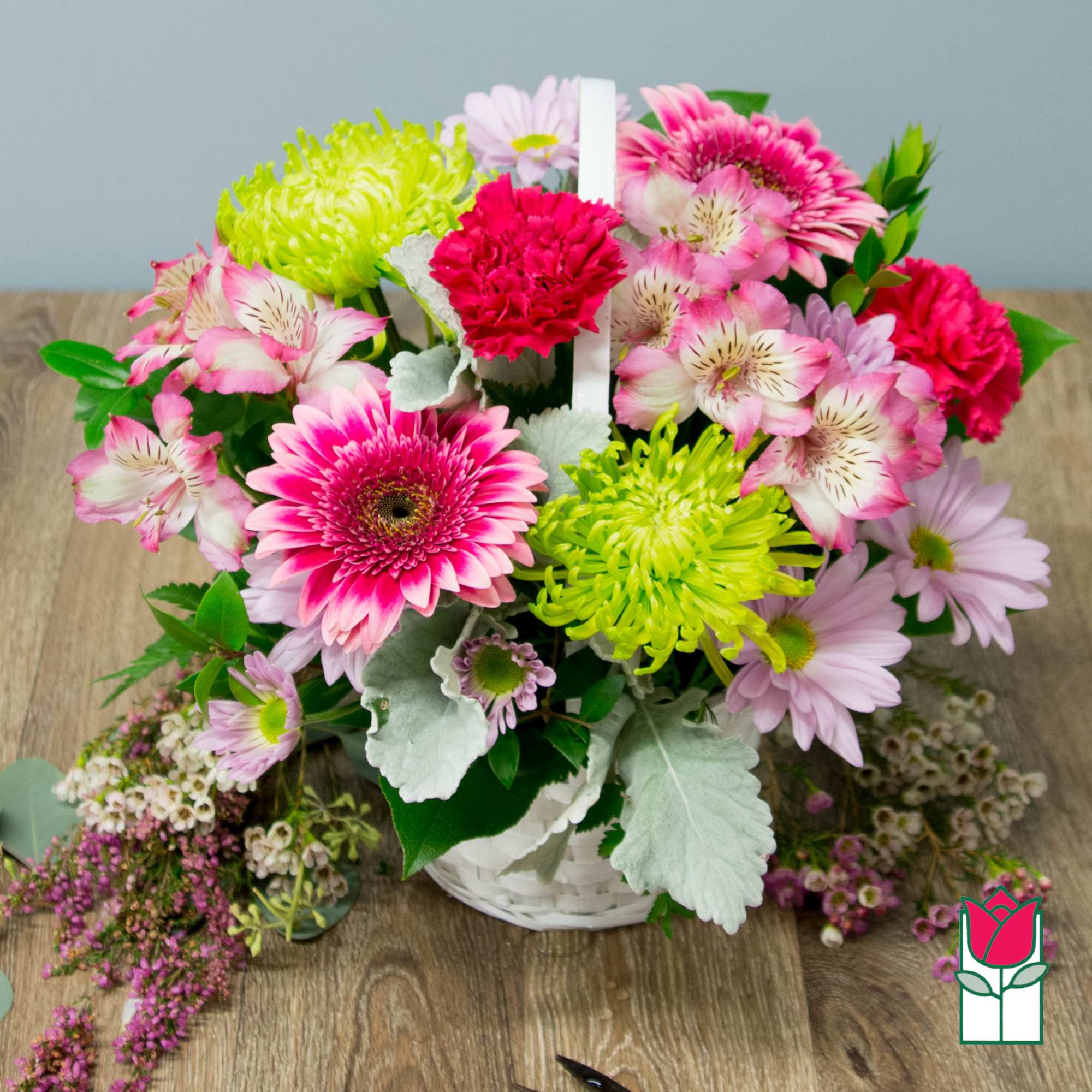 Mixed pink and lime flowers arranged in a white basket
