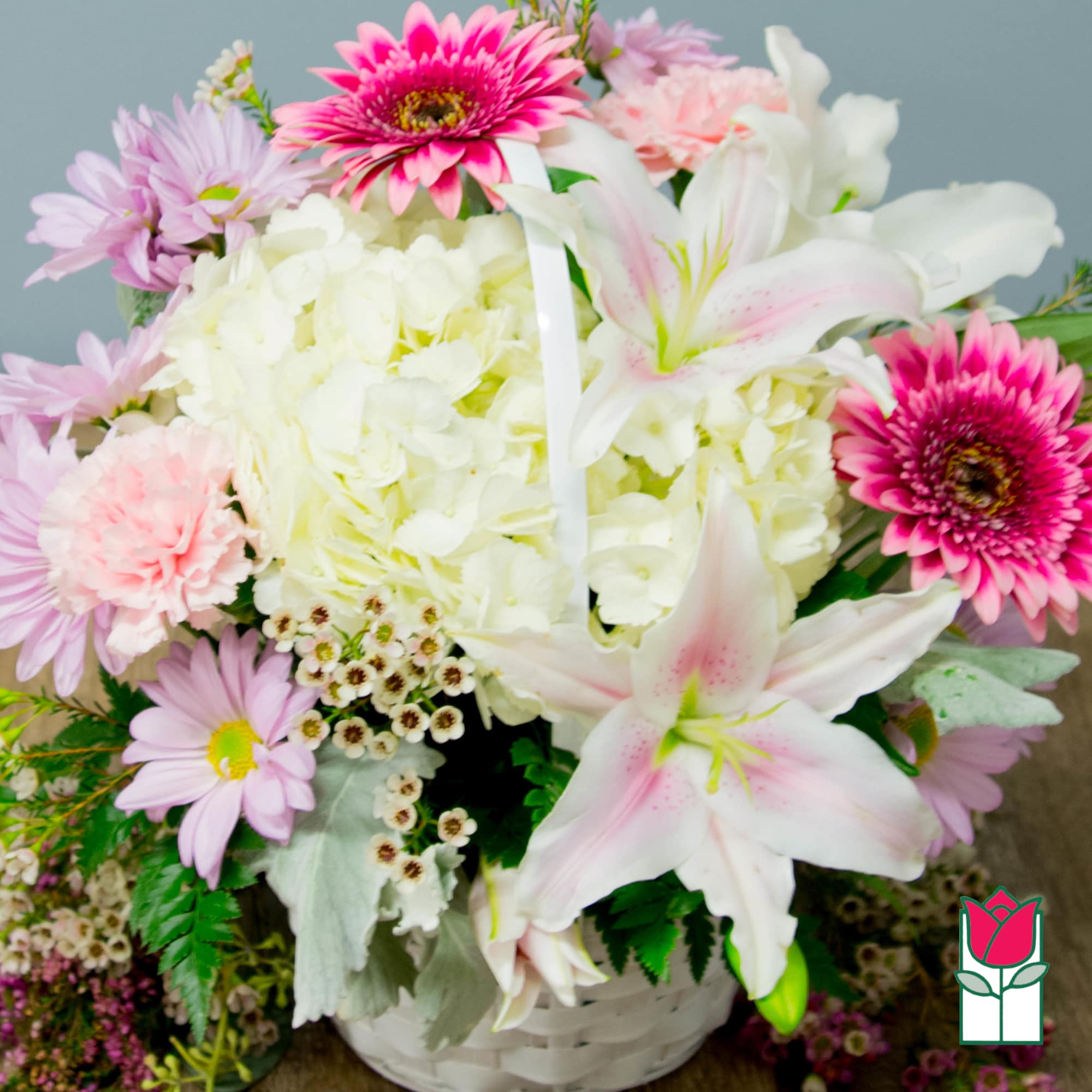Pink and white mixed bouquet with lilies, hydrangea, and daisies in a white basket