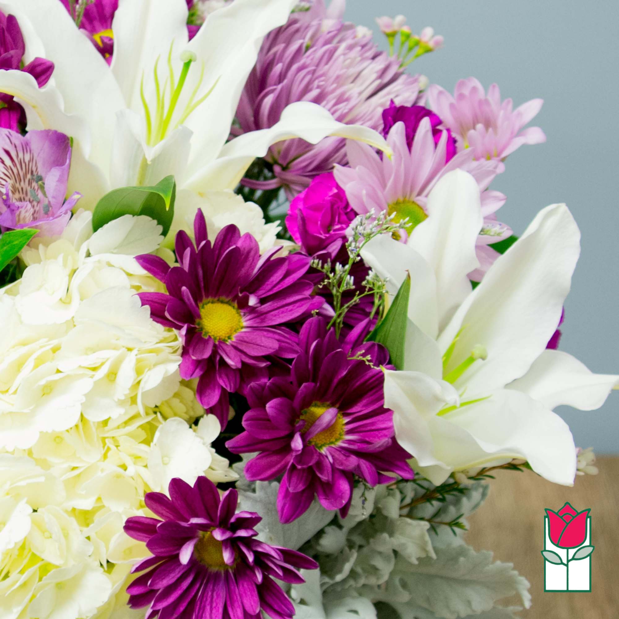 Bouquet of white lilies, purple daisies, and pale hydrangeas