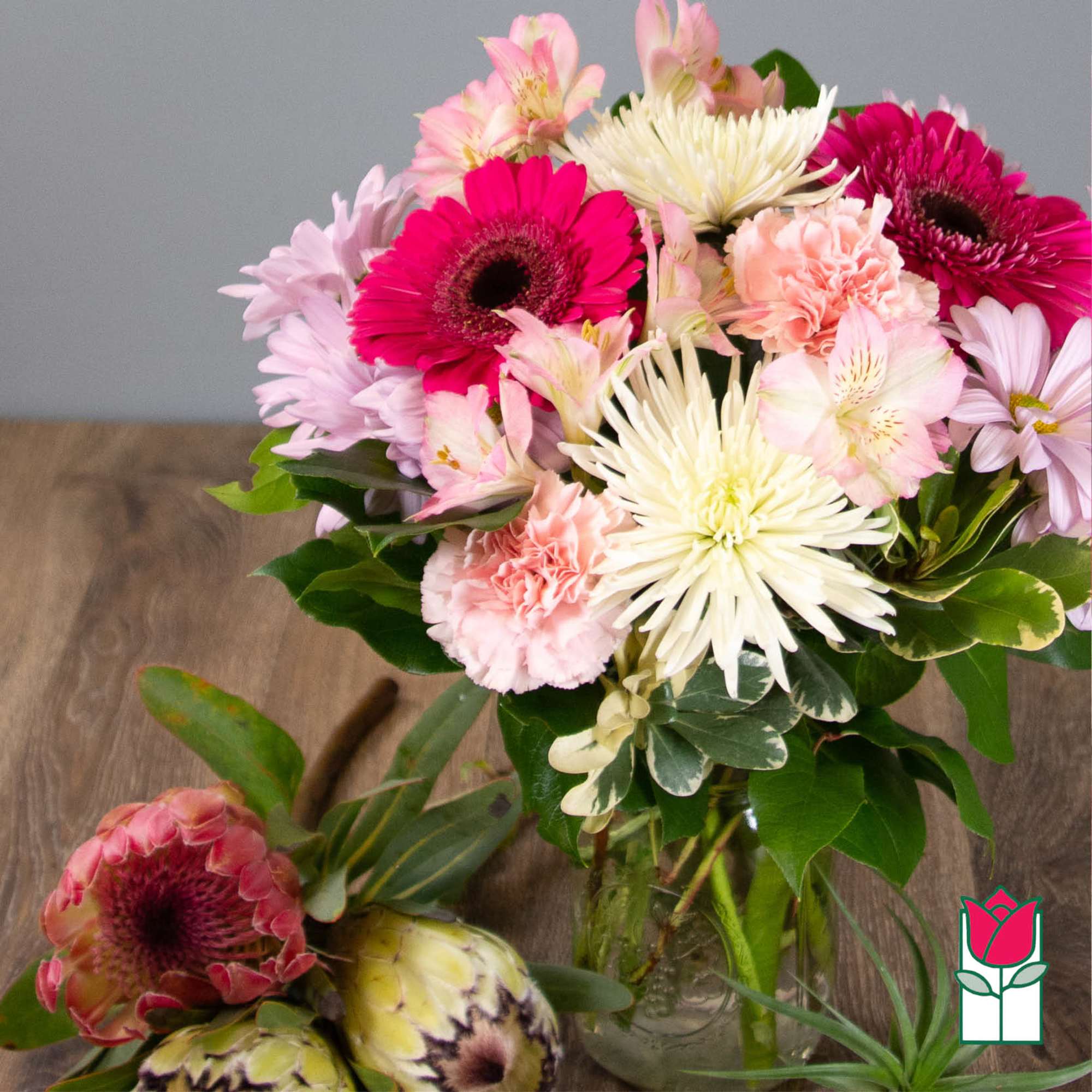 Mixed bouquet of pink, white, and peach flowers in a glass vase