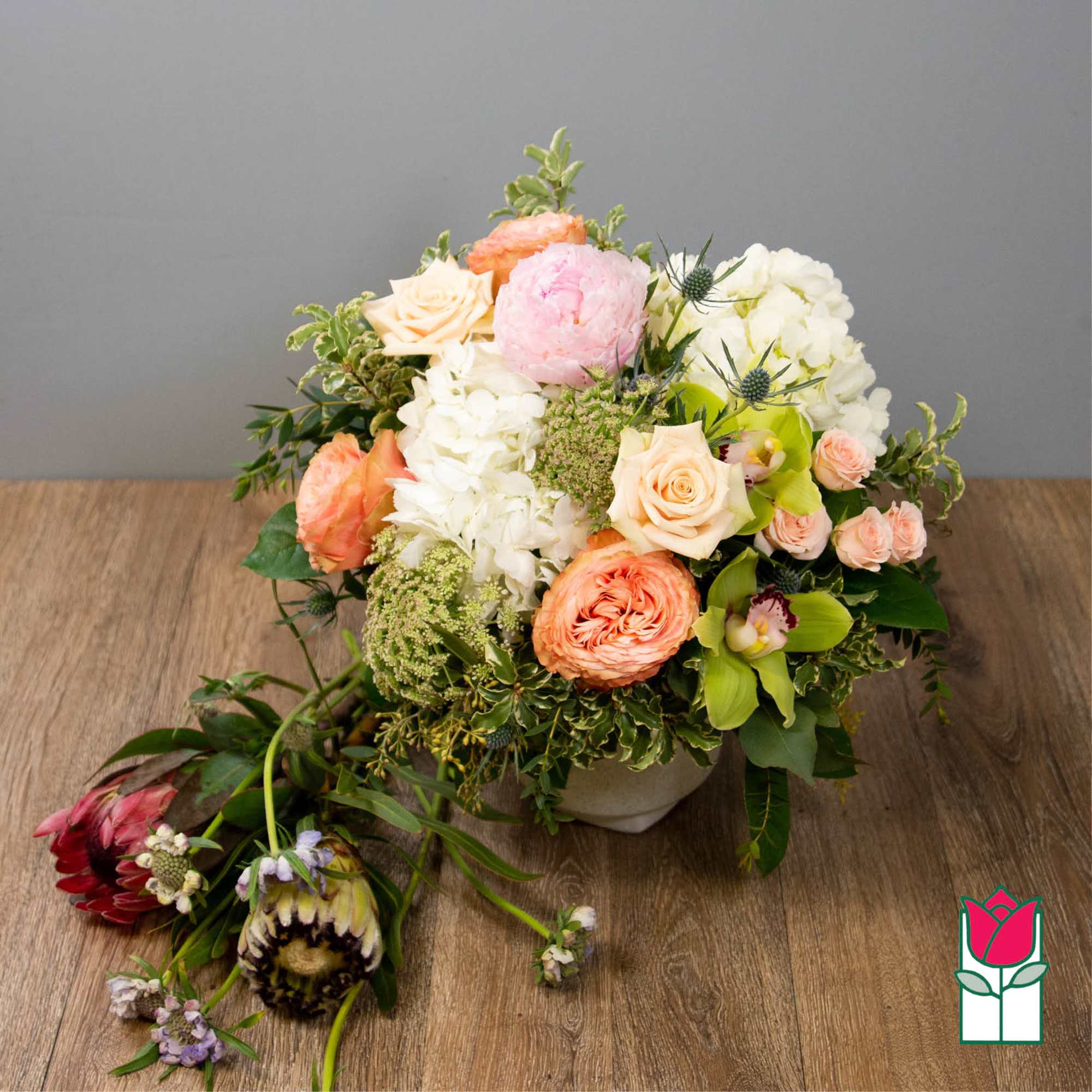 Mixed bouquet in a low white vase with peach, pink, and white blooms