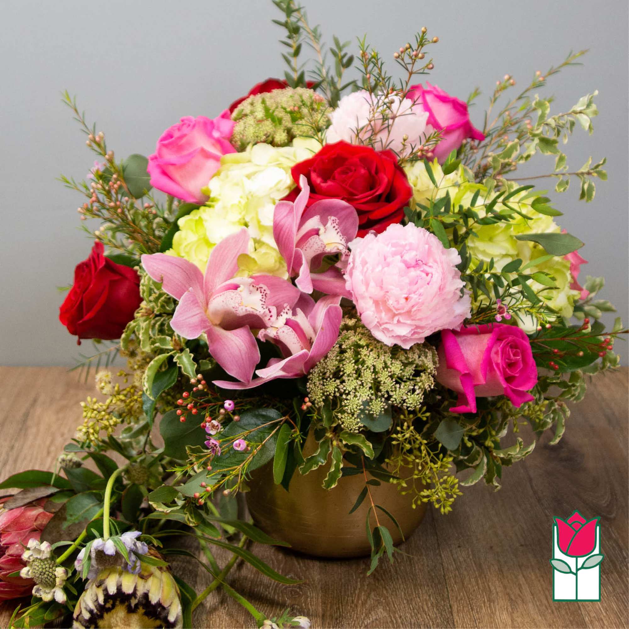 Bouquet of pink and red roses with orchids in a gold vase