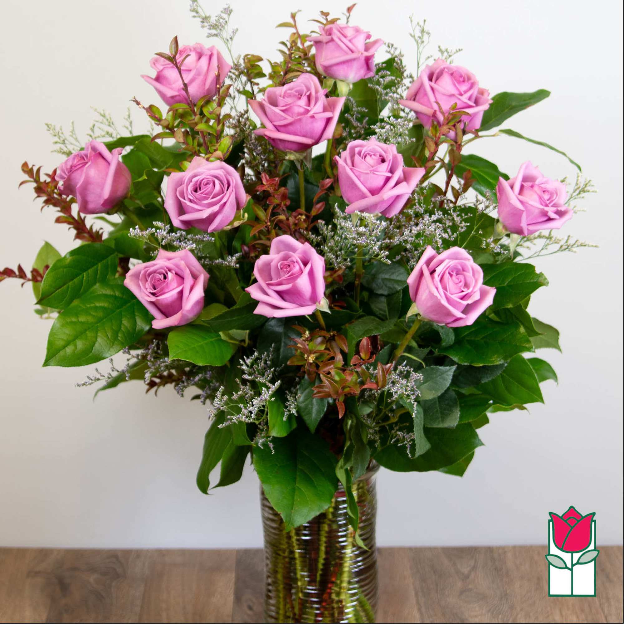 Pink roses arranged in a clear glass vase with mixed greenery