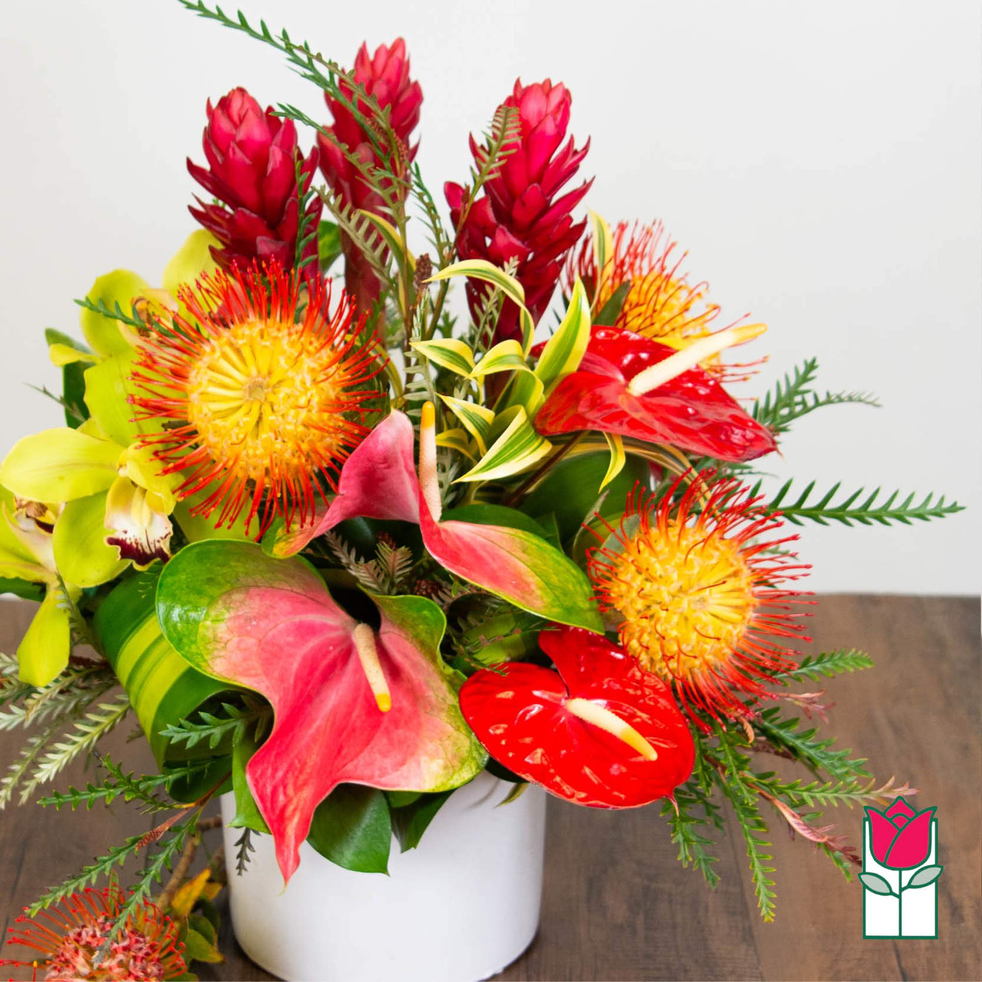 Tropical bouquet with red anthuriums and bright orange pincushion blooms in a white vase