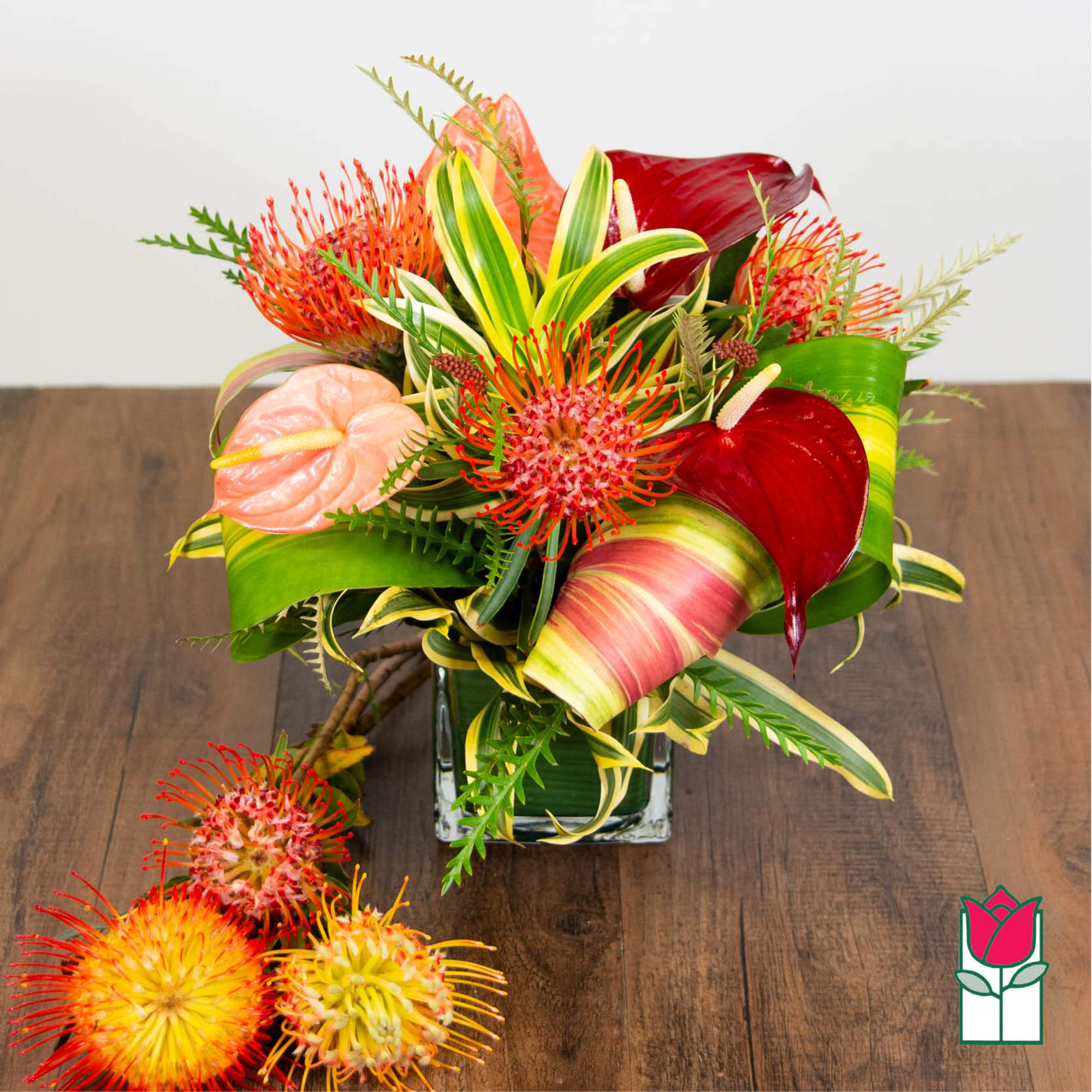 Tropical bouquet with red anthuriums and orange pincushion blooms in a glass vase, photo 2 of 4
