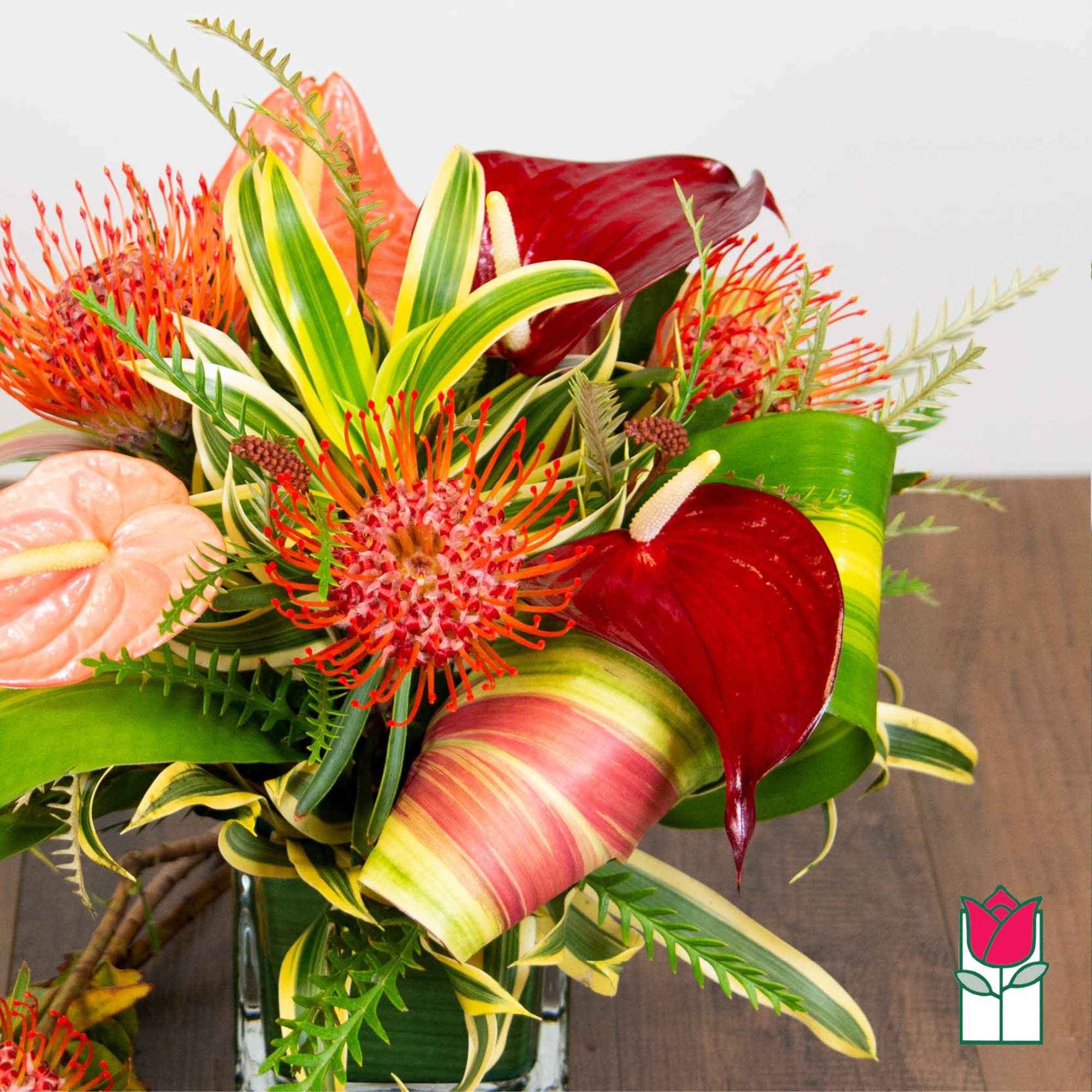 Tropical bouquet with red anthuriums and orange pincushion blooms in a glass vase, photo 3 of 4